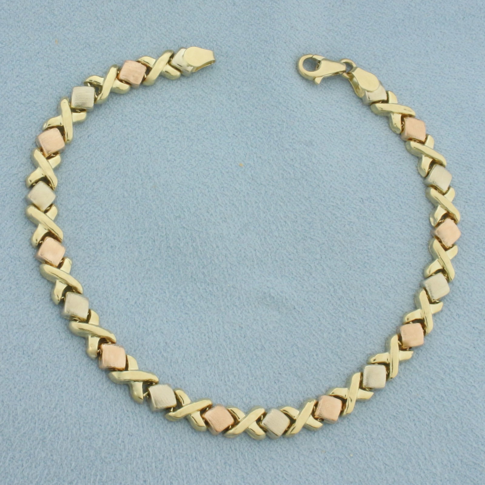 Tri-Color XO Bracelet in 14k Yellow, White, and Rose Gold: In 14k Yellow, White, and Rose Gold. 7 3/8 inches long. 4.9mm wide. Lobster clasp. 4.6g.