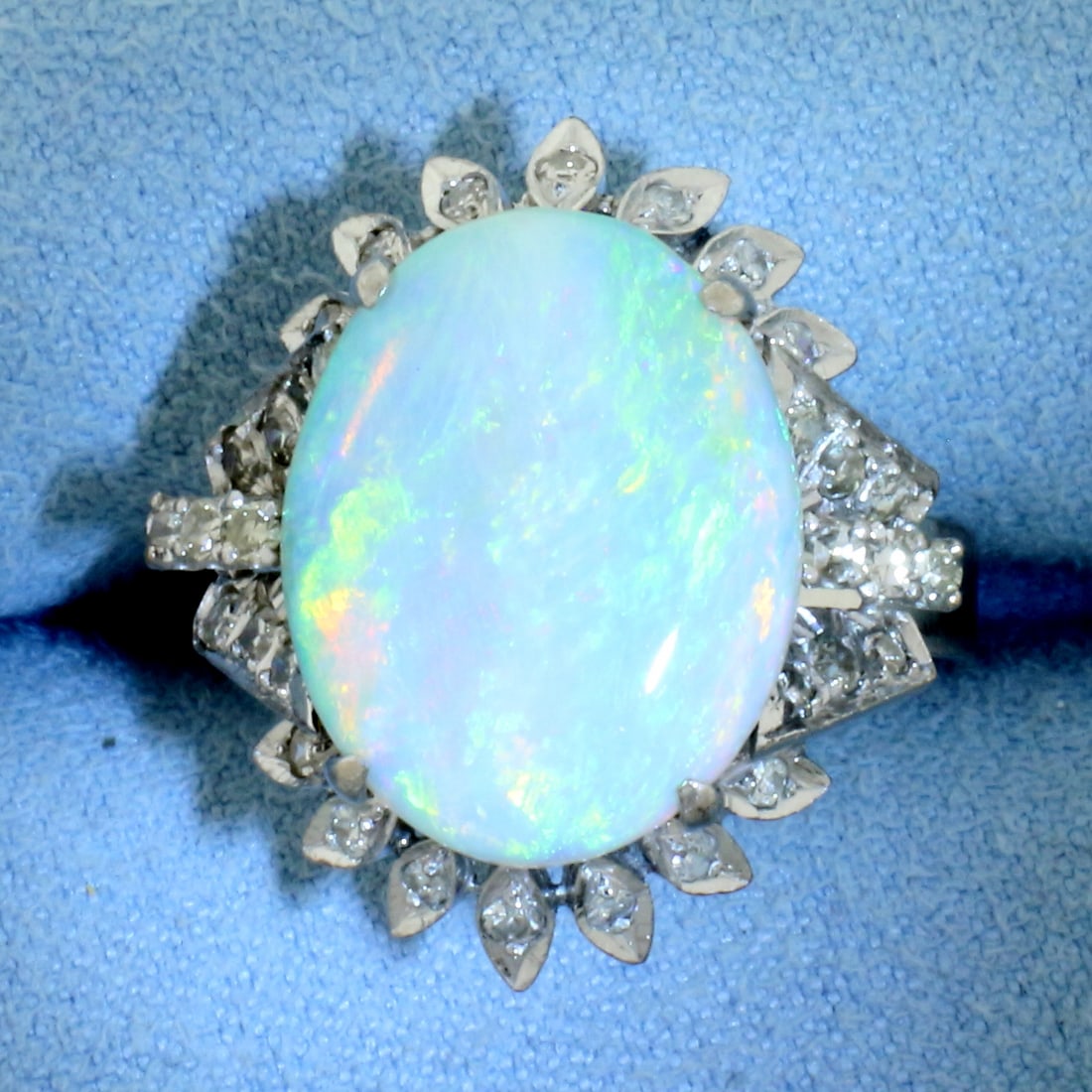 Opal and Diamond Halo Ring in 18k White Gold: In 18k White Gold. Contains one 16.5x13mm high quality natural Opal gemstone with intense play of color, flashes of green, blue, orange, and red. Also contains eighteen .02ct and fourteen .01ct high q