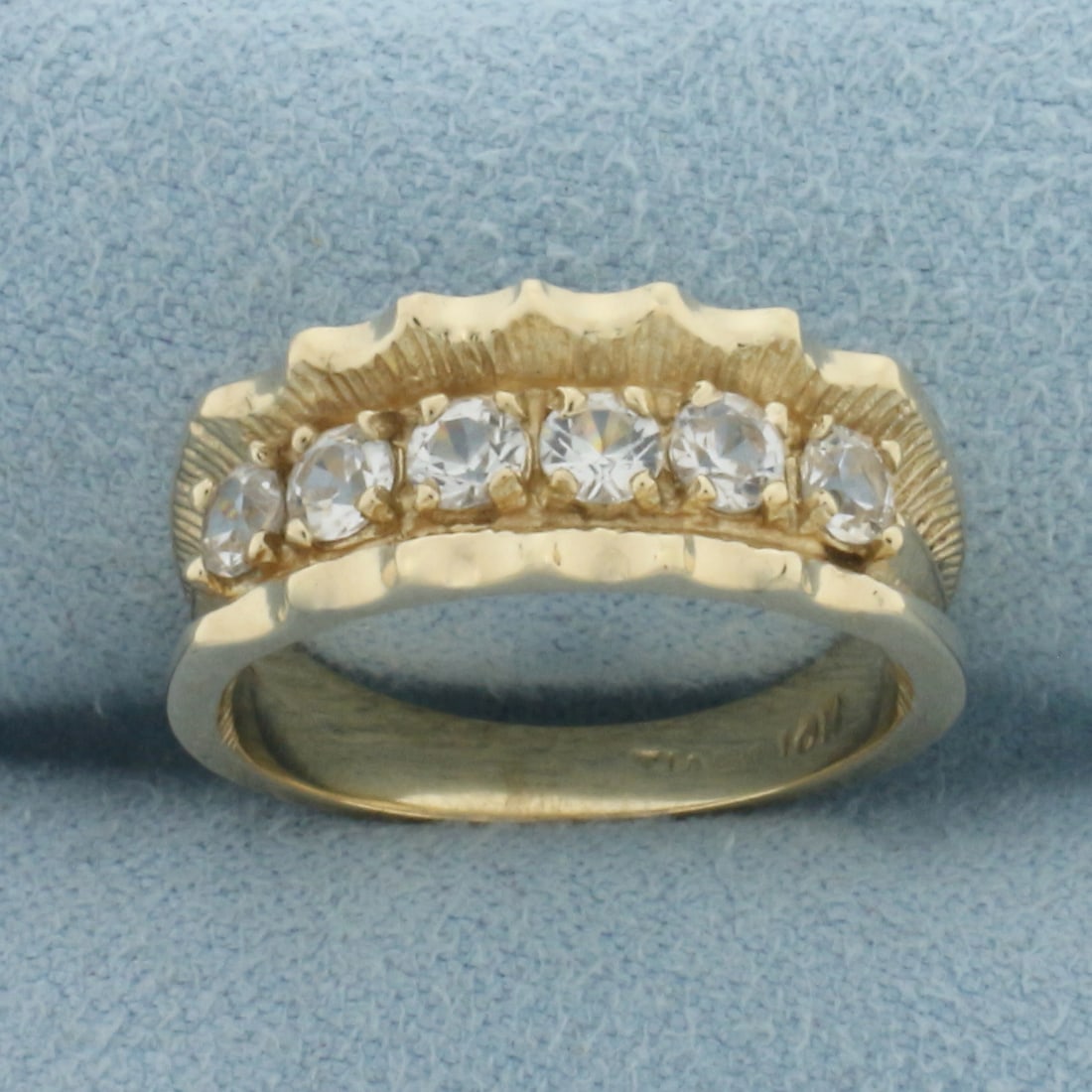 White Sapphire Band Ring in 10k Yellow Gold: In 10k Yellow Gold. Contains six 3.3mm high quality natural White Sapphire gemstones with excellent cut and clarity for added brilliance. 7.7mm wide at top of ring. Size 6. 4.5g.