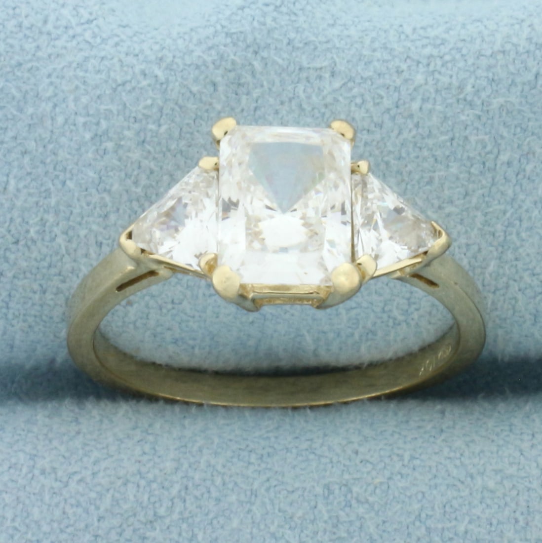 CZ 3-Stone Engagement Ring in 10k Yellow Gold: In 10k Yellow Gold. Contains one 8.5mmx6.5mm radiant cut and two 6mm trillion cut high quality cubic zirconia gemstones with excellent cut and clarity for added brilliance. Size 9. 3.8g.