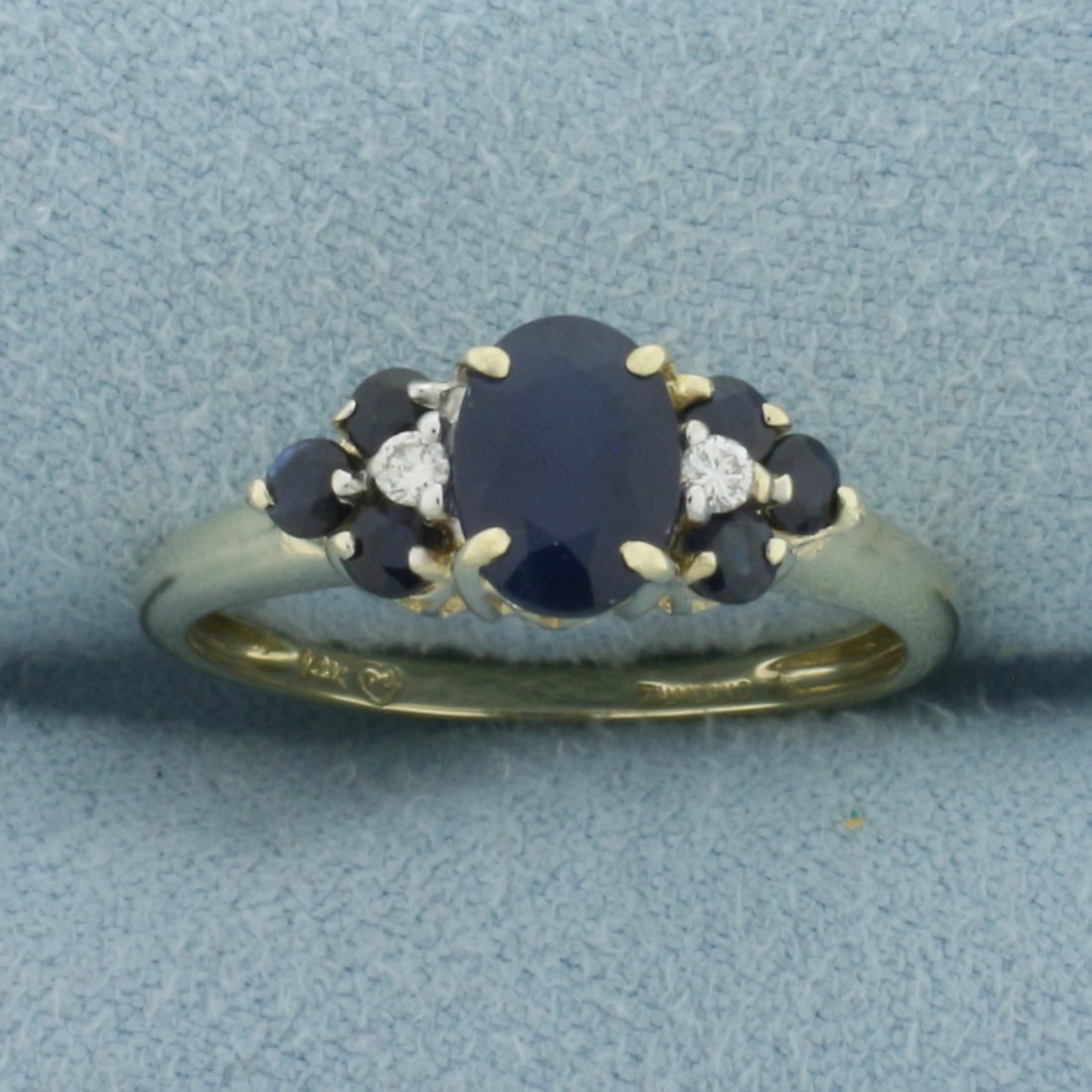 Sapphire and Diamond Ring in 14K Yellow Gold: In 14k yellow gold. Contains one oval cut high quality natural Sapphire gemstone, 7x5mm, 1 carat, with intense color and excellent clarity. Also contains six 2.3mm round Sapphire gemstones of similar 