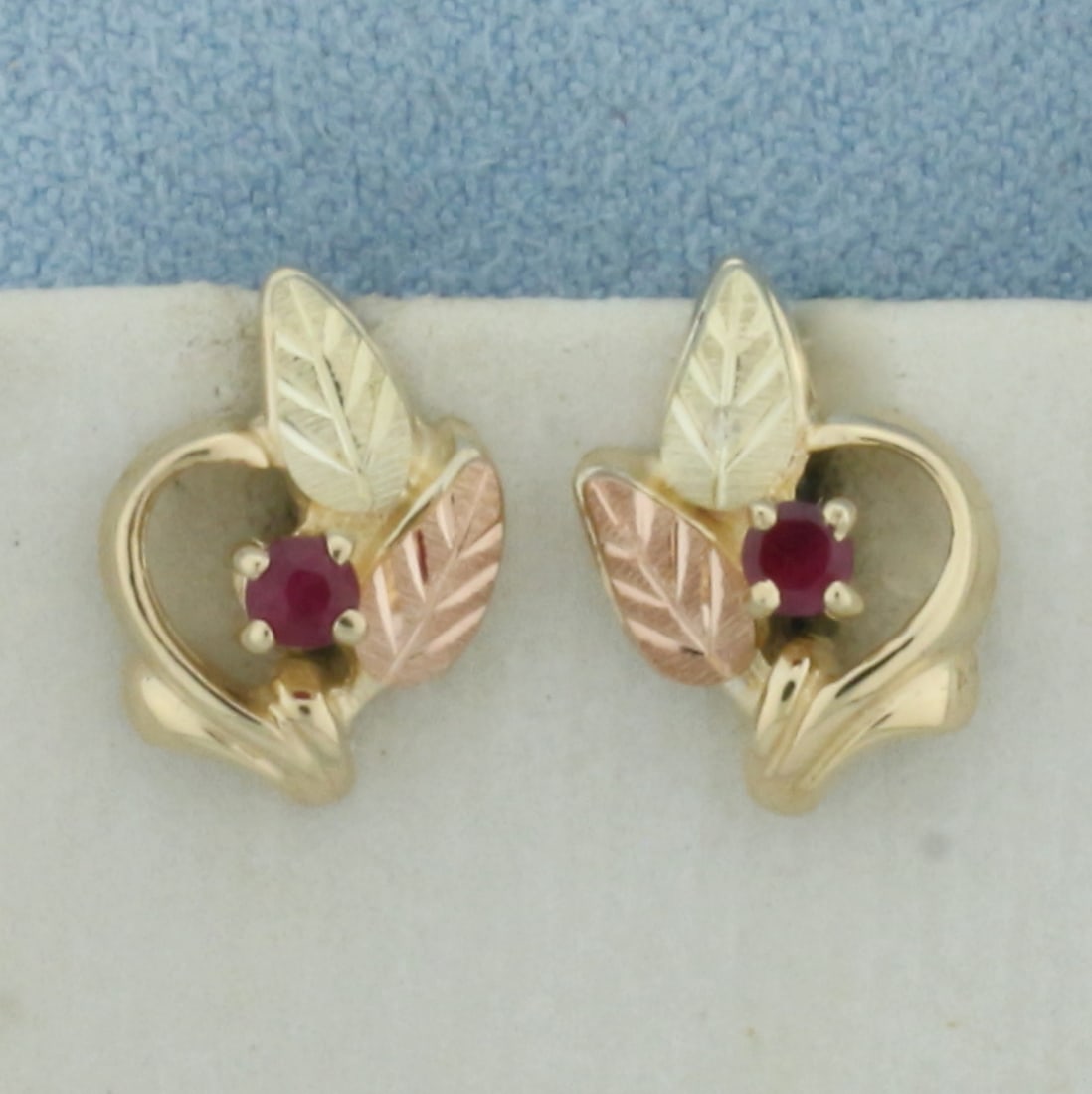 Ruby Tri Color Gold Leaf Earrings in 10K Yellow, Green, and Rose Gold: In 10K Yellow, Green, and Rose Gold. 1/2 inch long. 1/4 inch wide. Contains 2 high quality 2.5mm natural Ruby gemstones with vibrant color and excellent clarity. Friction backs. 2.4g.