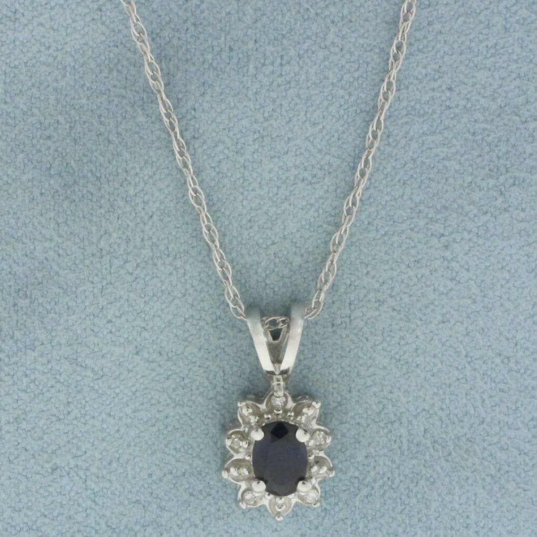 Sapphire and Diamond Halo Necklace in 14K White Gold: In 14k white gold. Chain is 20 inches long, 1.1mm wide, with spring clasp. Contains one high quality natural 6x4mm Sapphire gemstone, with intense color and excellent clarity. Accented with 5 high qua