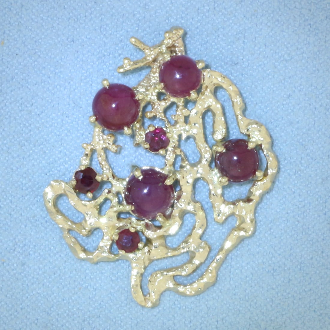 Star Ruby Pendant in 14k Yellow Gold: In 14k yellow gold. 1 1/4 inch long by 1 inch wide. Contains 4 high quality Star Ruby gemstones, 5-5.6mm each, with distinct "star" under light. Also contains three 3mm Ruby gemstones with intense col