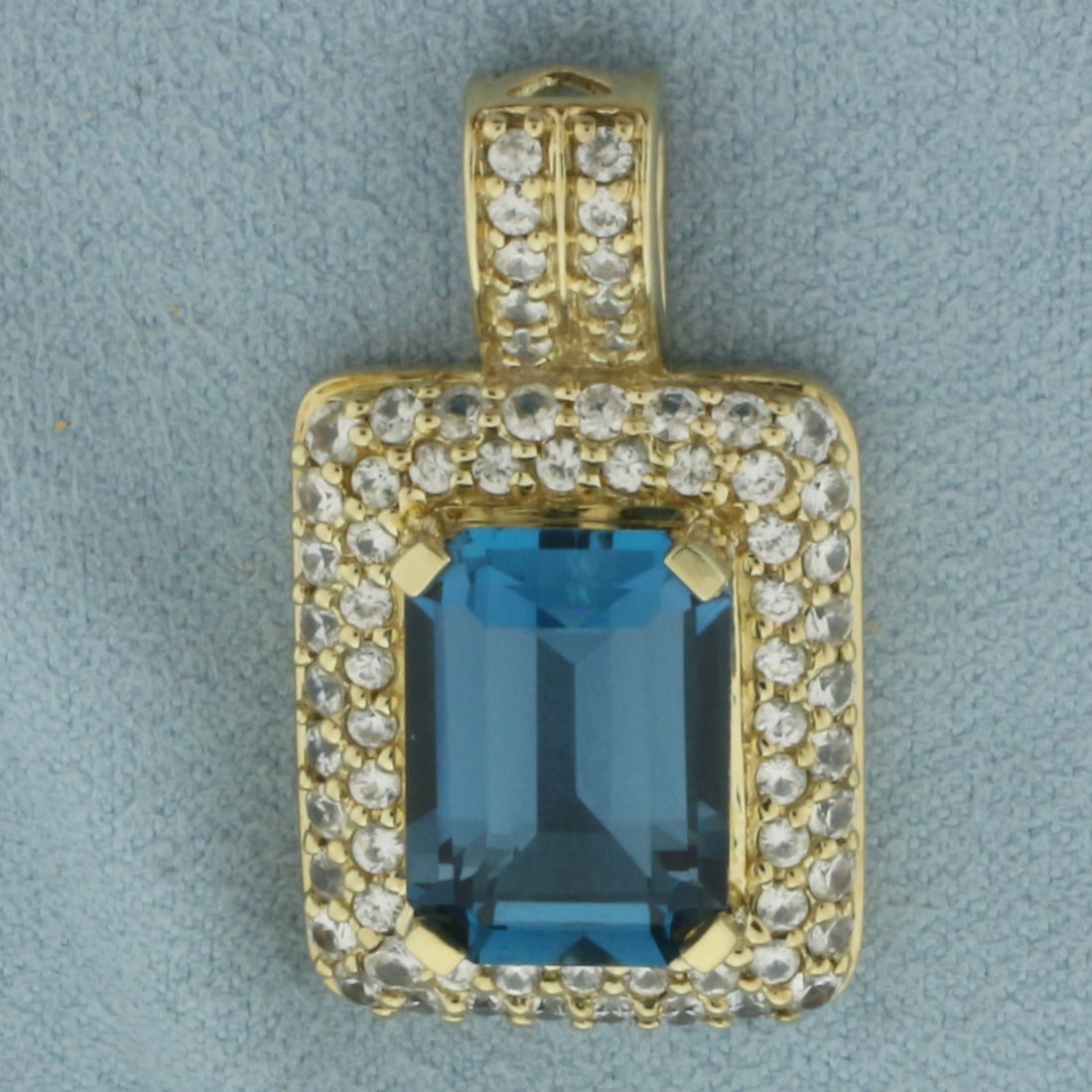 London Blue Topaz and White Sapphire Pendant in 10K Yellow Gold: in 10k yellow gold. 1 1/4 inches long by 3/4 inch wide. Contains 1 emerald cut London Blue Topaz, 14x10mm,approximately 9cts, with deep blue color and excellent clarity. Accented with sixty 1.75mm hig