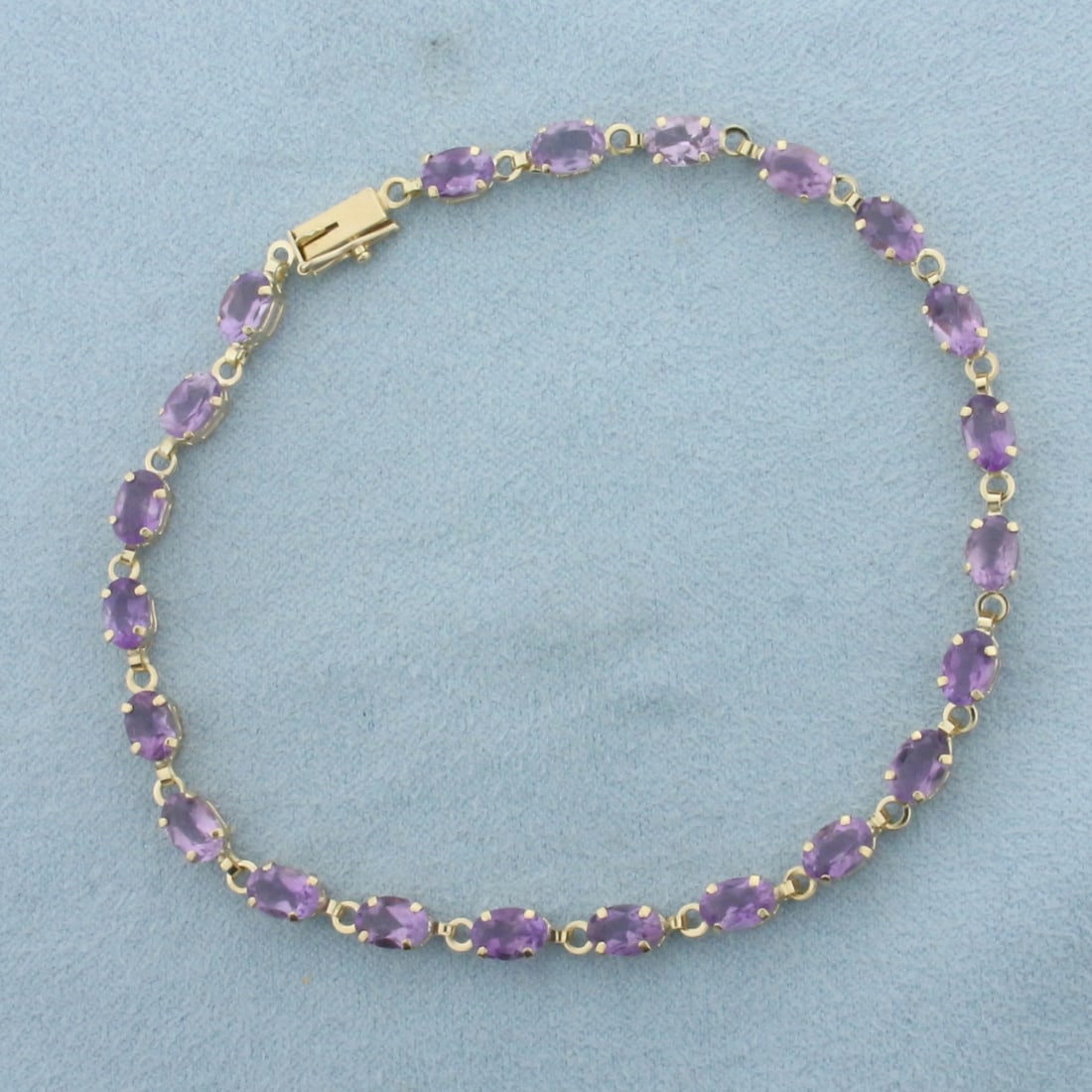 Amethyst Tennis Bracelet in 10k Yellow Gold: In 10k Yellow Gold. Contains twenty-two 6x4mm high quality natural Amethyst gemstones with rich color and excellent clarity. 8 3/8 inches long. 4mm wide. Slide clasp with safety latch. 5.1g.