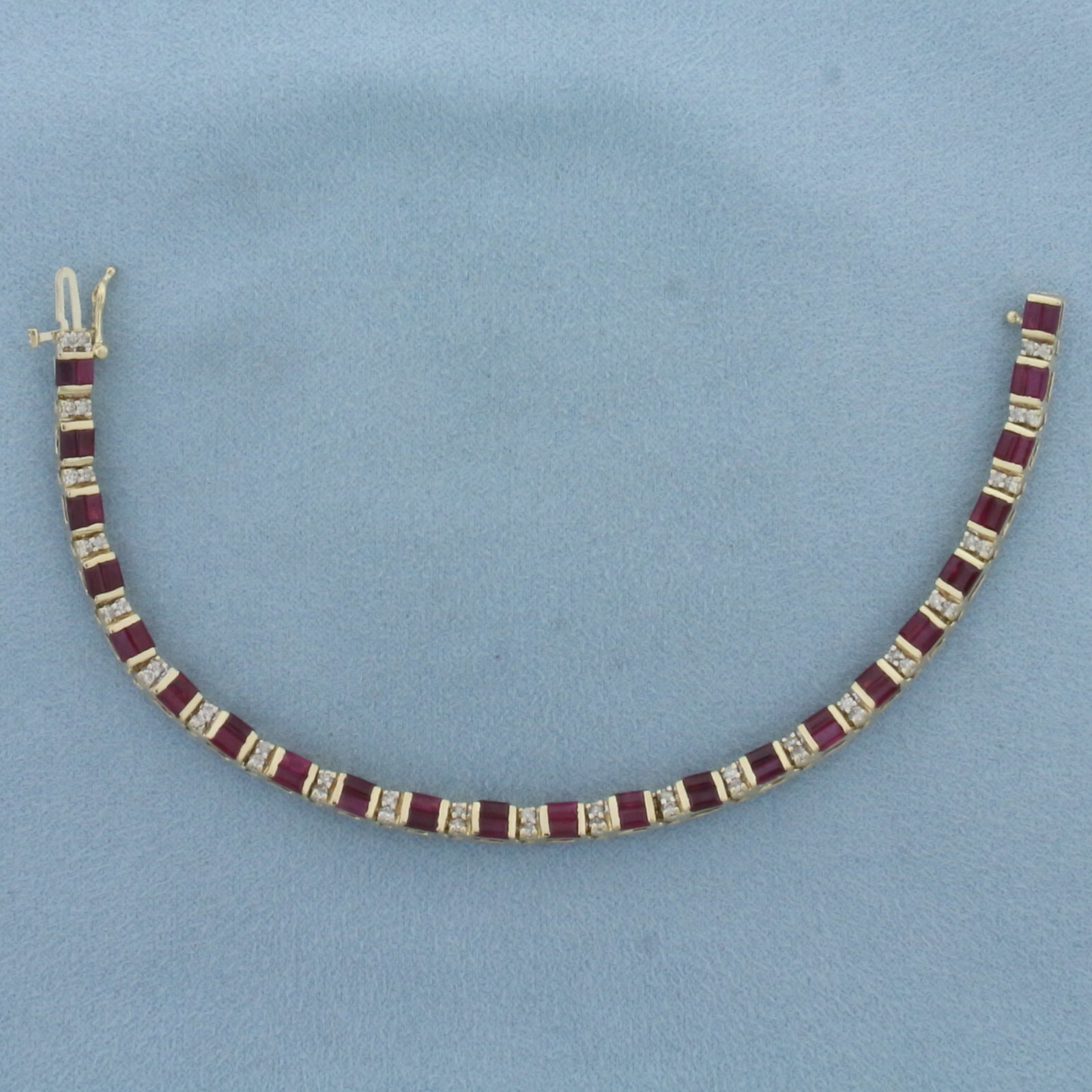 Ruby and Diamond Tennis Bracelet in 14k Yellow Gold: In 14k Yellow Gold. Contains forty-six 4x2mm high quality emerald cut natural Ruby gemstones with intense color. Also contains forty-six .01ct high quality diamonds. 7 inches long. 4mm wide. Concealed