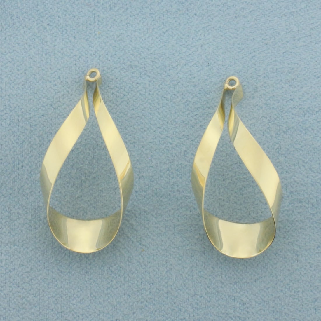 Twisting Ribbon Teardrop Stud Earring Enhancers in 14k Yellow Gold: In 14k Yellow Gold. 1 1/8 inch long. 1/2 inch diameter. 6.3mm wide at widest point. Made to dangle from stud earrings to give a fresh new look. 1.3g.
