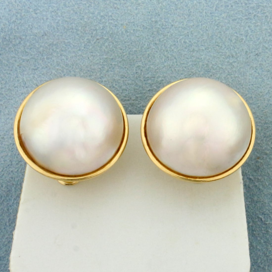 Mabe Pearl Earrings for Non pierced Ears In 14K Yellow Gold: In 14K Yellow Gold. Each Earring Contains One High Quality Natural 19.5mm Mabe Pearl, with high luster and iridescent undertones. 3/4 inch long. Omega backs for non pierced ears. Can add post for smal