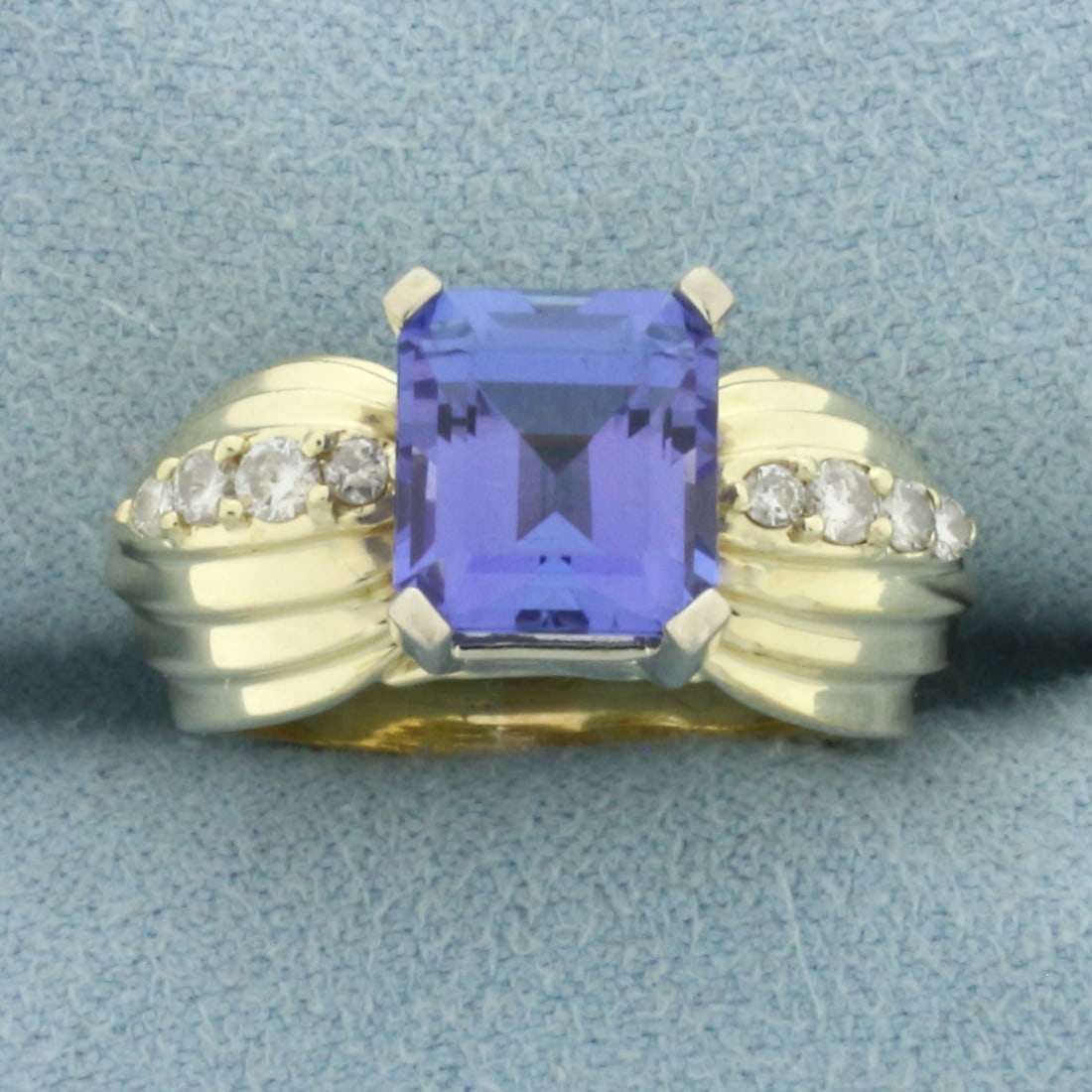 Designer Tanzanite and Diamond Ring in 14k Yellow Gold: In 14k Yellow Gold. Contains one high quality AAA quality natural 3ct emerald cut Tanzanite gemstone with intense color and excellent clarity. Also contains eight high quality diamonds, 1/5ct TW, SI c