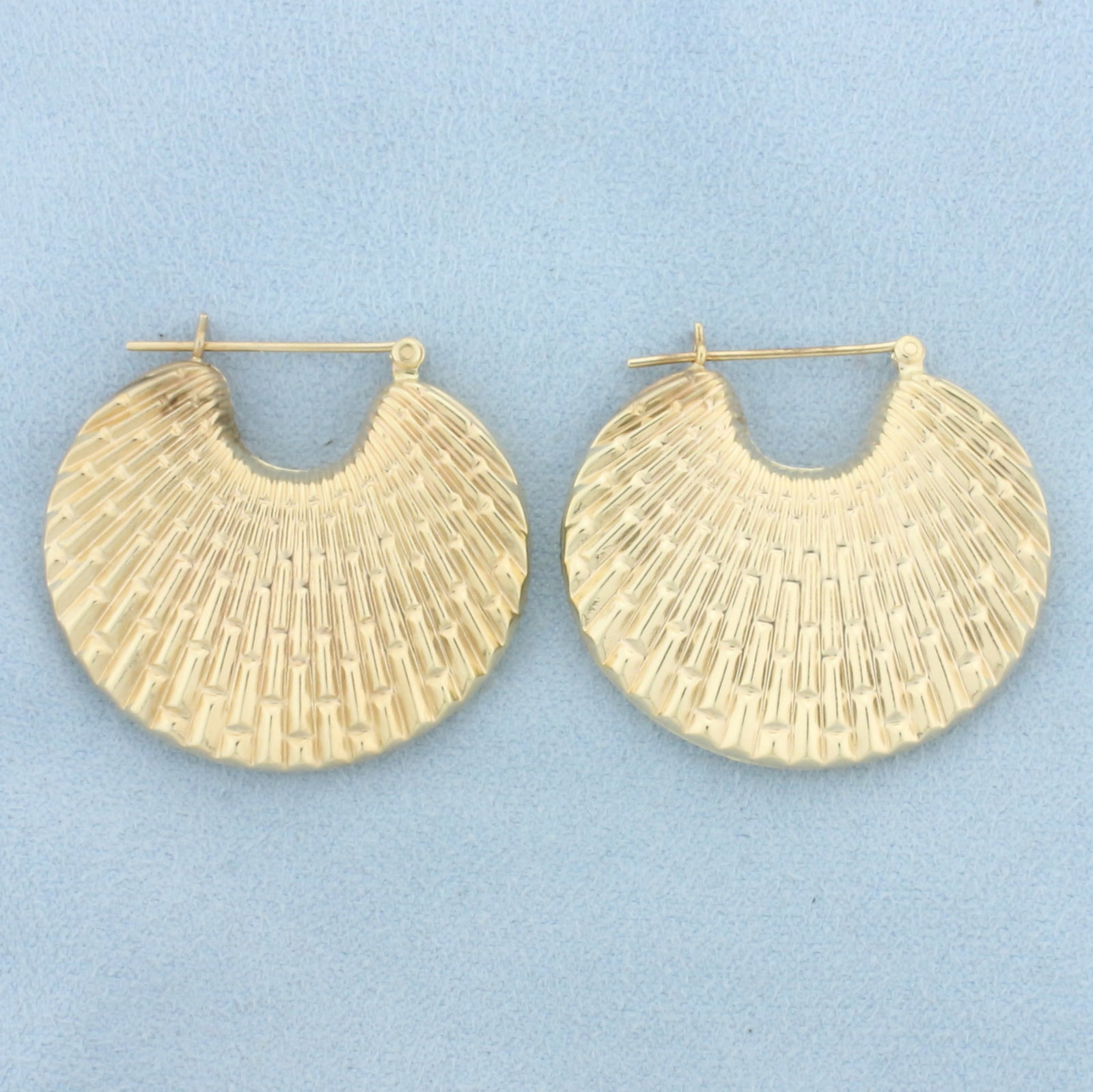 Textured Fan Design Hoop Earrings in 14k Yellow Gold: In 14k Yellow Gold. 1 1/4 inches long. 1 3/8 inches wide. Unique design gives extra reflection. 8.2g.