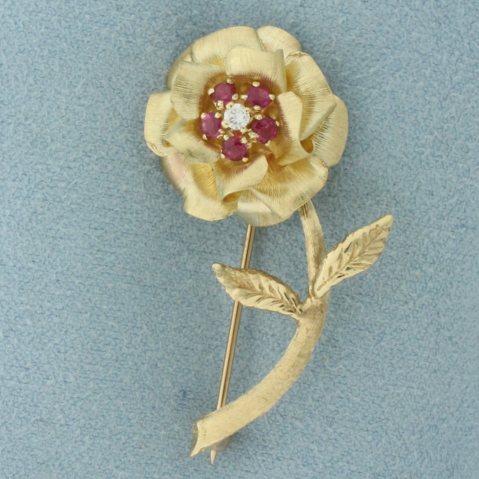 Ruby and Diamond Rose Flower Brooch Pin in 14K Yellow Gold: In 14k yellow gold. 1.5 inches long by 3/4 inches wide. Contains five high quality natural 2.5mm Ruby gemstones with vibrant color and excellent clarity. Also contains one high quality .05ct diamond, 