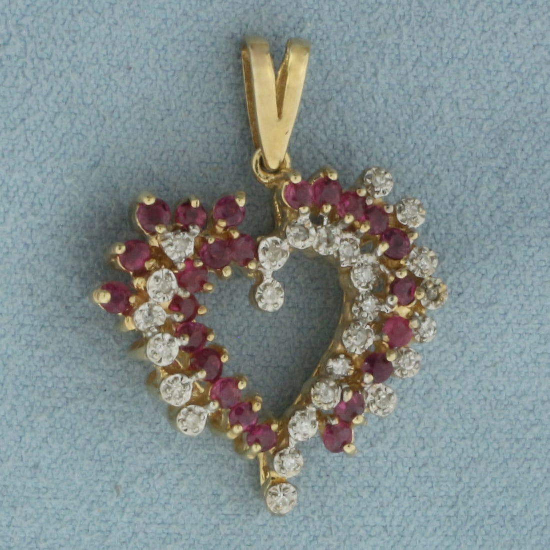 Ruby and Diamond Heart Pendant in 10K Yellow Gold: In 10k yellow gold. 1 1/8 inches long by 7/8 inch wide. Contains twenty four high quality natural 2mm Ruby gemstones with vibrant color. Also contains 26 high quality 1/2pt diamonds. 4.3g.