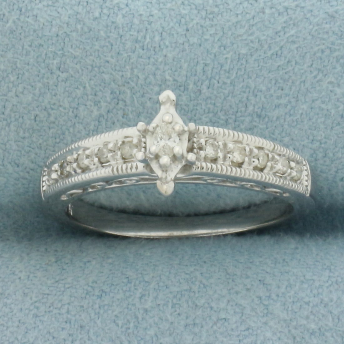 Marquise Diamond Engagement Ring in 10K White Gold: In 10k white gold. Contains 1 marquise cut diamond, 3.5x2.2mm, approximately 1/10ct, VS clarity/G color. Accented with 10 round .01ct diamonds of similar high quality. Milgrain detailing. Size 7.5. 3.