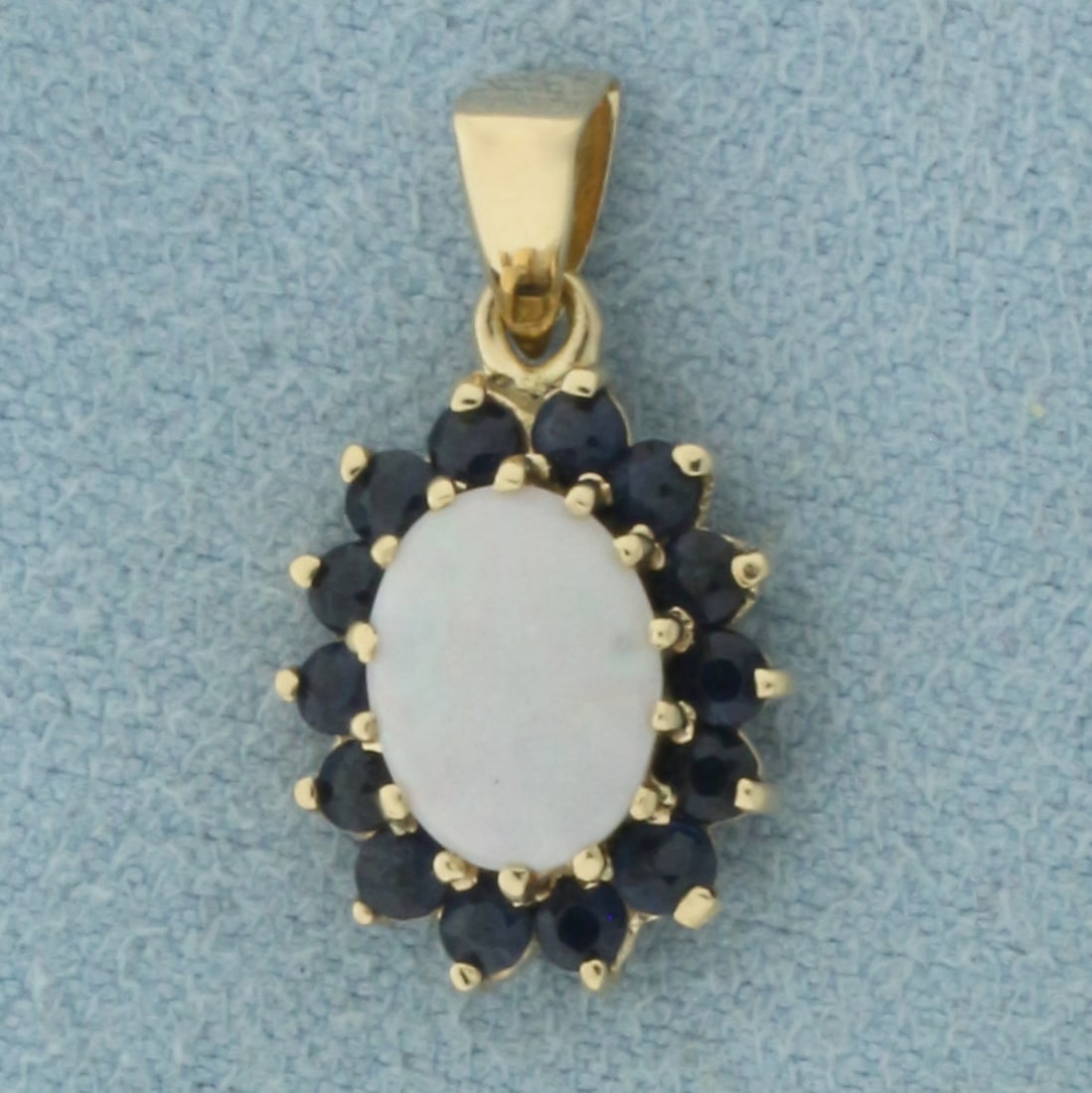 Opal and Sapphire Pendant in 14K Yellow Gold: In 14k yellow gold. 3/4 inch long (including bail) by 3/8 inch wide. Contains 1 high quality natural 8x6mm Opal gemstone with excellent play of color, flashes of green, yellow, orange, and red. Accent