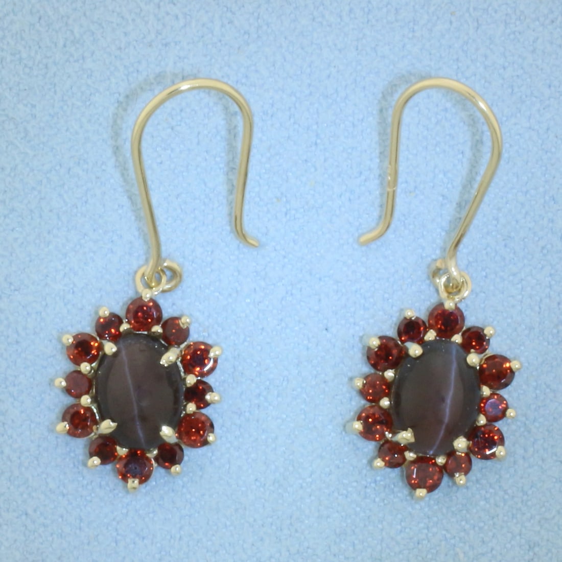 Cats Eye Garnet Dangle Halo Earrings in 10K Yellow Gold: In 10k yellow gold. 1 1/8 inch long by 3/8 inch wide each. Contains 2 high quality natural 8.5x6.5mm Catseye Garnet gemstones with distinct "eye" under light. Also contains twelve 3mm and twelve 2.5mm