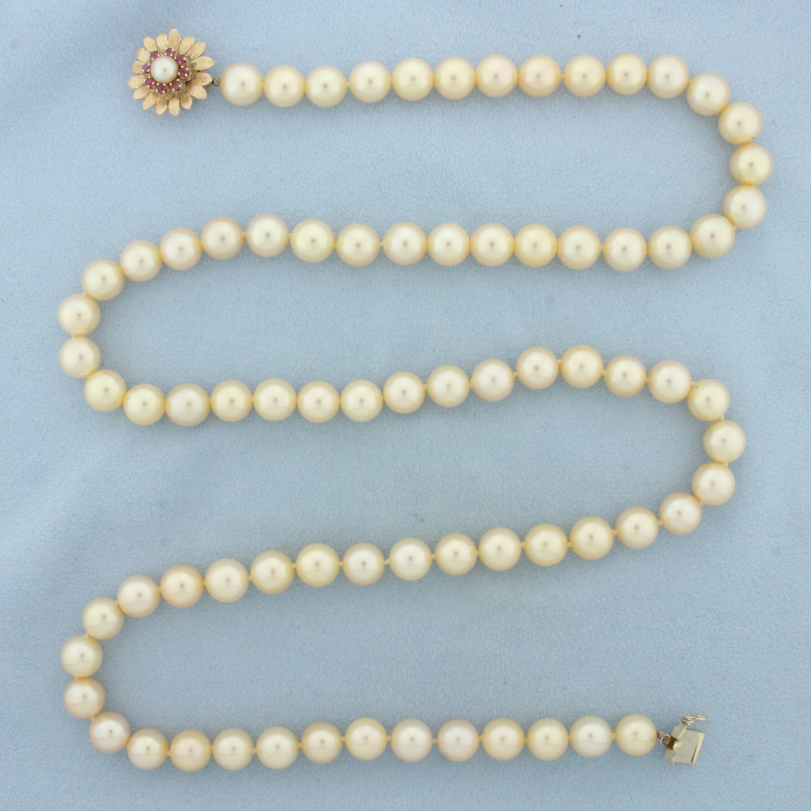South Sea Golden Pearl Necklace with Ruby Flower Clasp in 14K Yellow Gold: With 14k yellow gold decorative locking clasp with safety latch. 30.5 inches long, hand knotted. Contains 9-9.4mm high quality Cultured South Sea pearls with creamy golden color and high luster. Clasp