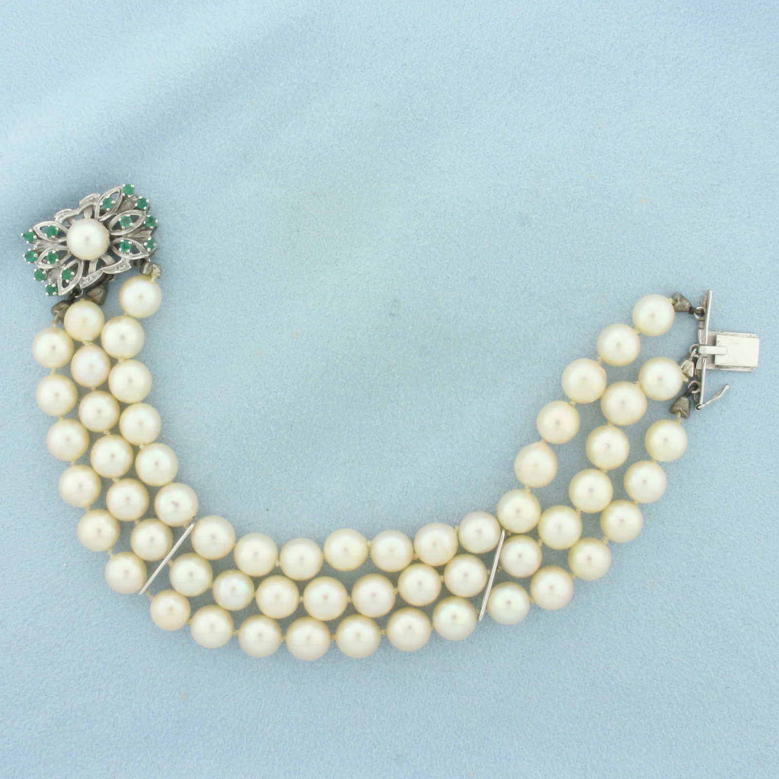Emerald and Cultured Akoya Pearl 3 Strand Bracelet in 14K White Gold: 14k white gold decorative slide clasp with safety latch. 7 3/4 inches long by 1 inch wide. Contains high quality 7.5-8mm Cultured Akoya Pearls with high luster. Hand knotted. Accented with 14 natural 