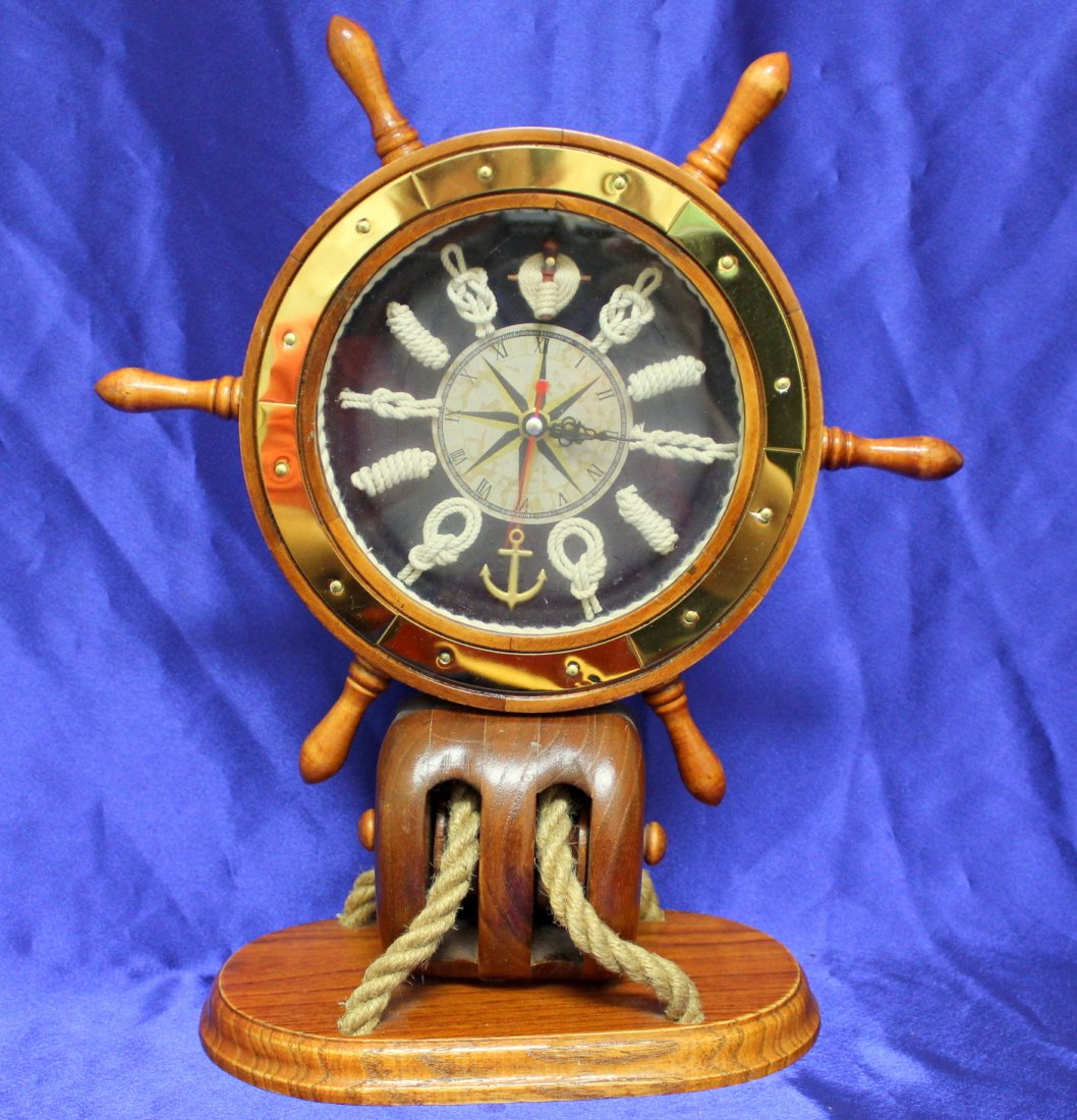 Ships Wheel Clock: This very attractive Ships Wheel Clock is made of Pine, is battery ran, and keeps good time. Measures 13" tall x 11 1/2" wide. Dial has different knots for time markers and a compass rose at the cente