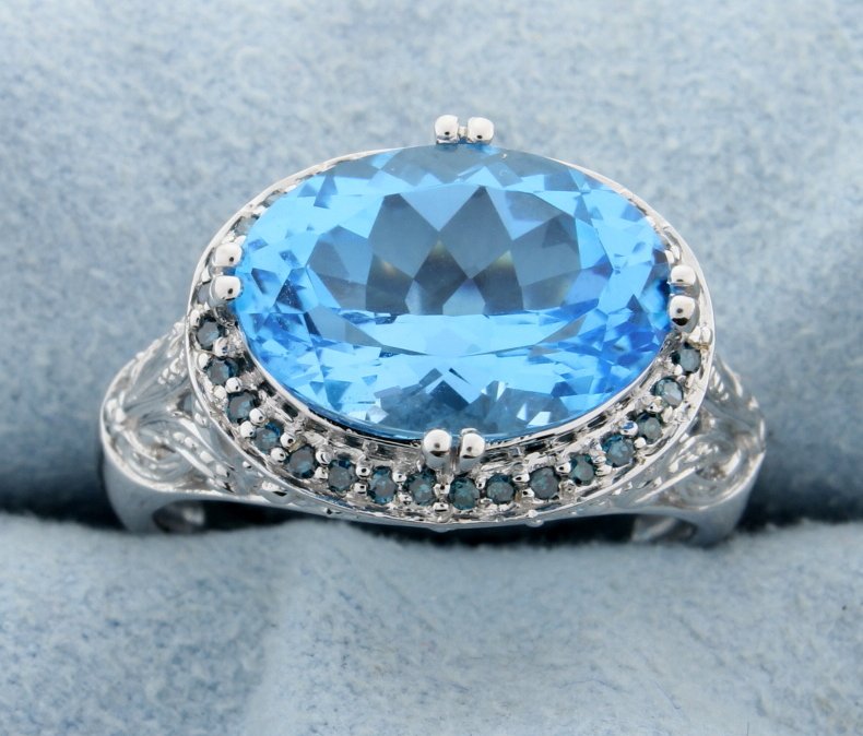 Blue Topaz & Diamond ring: What a fantastic look this ring has to offer! Set in 14k white gold this huge oval cut Blue Topaz colored center is surrounded by small London Blue Topaz colored stones and accented with 8 diamonds in