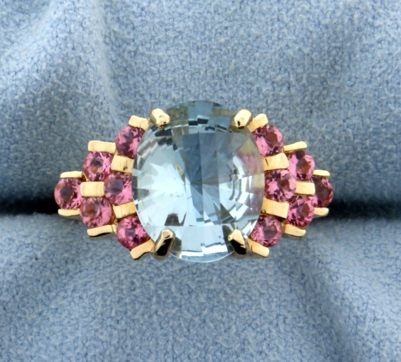 5ct Aquamarine and Morganite Ring: In 14K yellow gold the center stone is 5ct oval shape aquamarine gemstone with great color and unique cut. This ring also has twelve 3mm round morganite gemstones surrounding the center stone. Size 6 