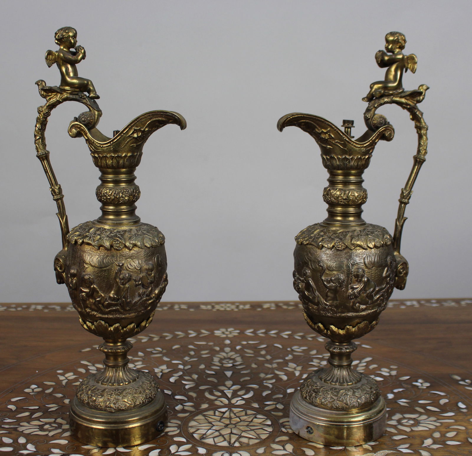Pair of 19th Century French Gilt Bronze Bacchanalian Ewers with Cherubs: Title:Pair of 19th Century French Gilt Bronze Bacchanalian Ewers with Cherubs Description: Pair of 19th Century French Gilt Bronze Bacchanalian Ewers with Cherubs A fine and decorative pair of