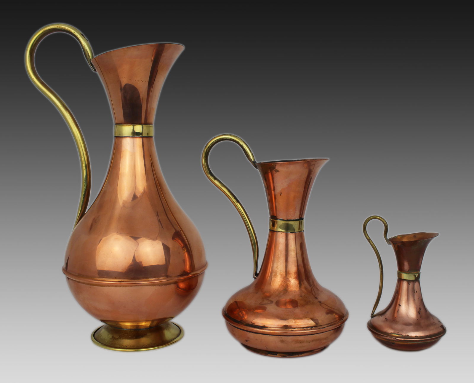 Set of 3 Graduated Vintage Copper Ewers: Title:Set of 3 Graduated Vintage Copper Ewers Description: Set of 3 Graduated Vintage Copper and Brass Ewers A decorative trio of vintage copper ewers in graduated sizes, with sweeping brass