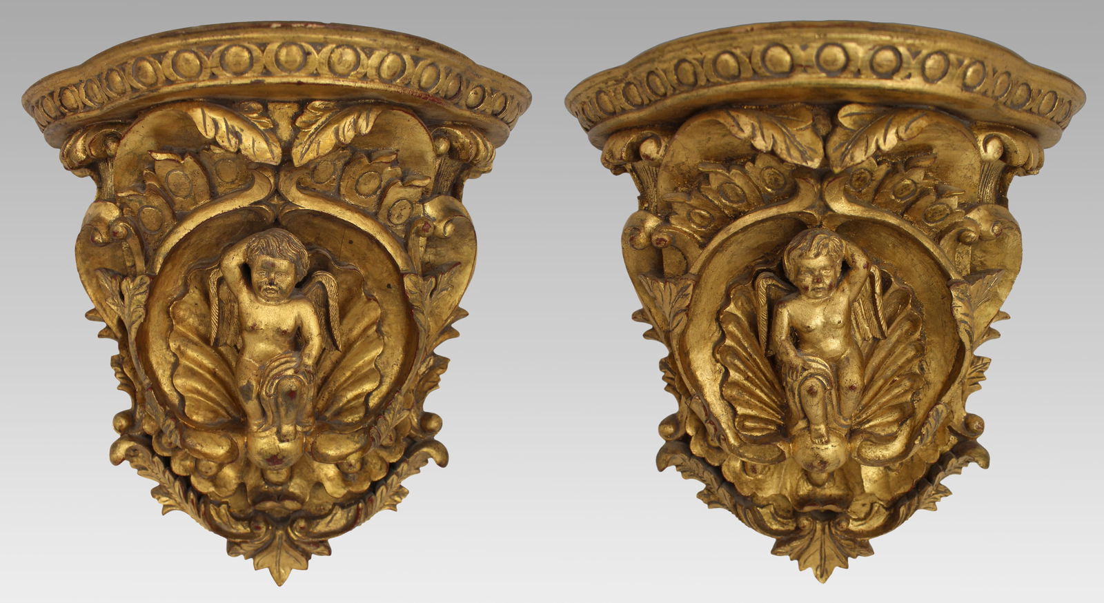 Pair of Carved Giltwood Wall Brackets with Cherub Motifs: Title: Pair of Carved Giltwood Wall Brackets with Cherub Motifs Description: Pair of Italian Baroque Revival Giltwood Wall Brackets with Cherub Motifs, Mid-20th Century A decorative an