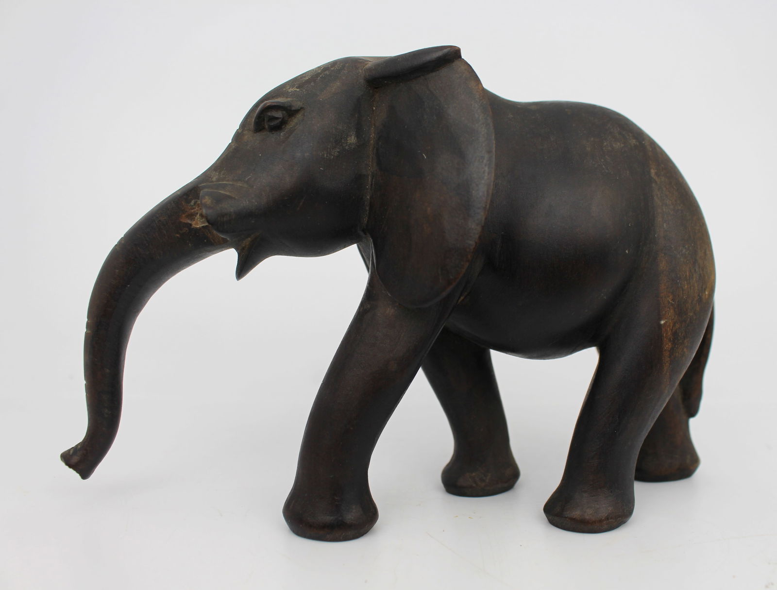 Vintage Hand-Carved Wooden Elephant: Title: Vintage Hand-Carved Wooden Elephant Description: Vintage Hand-Carved Wooden Elephant A carved wooden elephant figure with a dark, aged finish. The piece is carved from a single block of