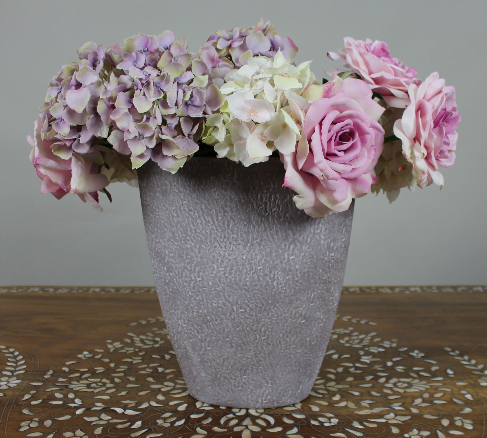 Decorative Floral Arrangement in Textured Grey Vase: Title: Decorative Floral Arrangement in Textured Grey Vase Description: Decorative Floral Arrangement in Textured Grey Vase Decorative arrangement of pink roses and lilac hyd