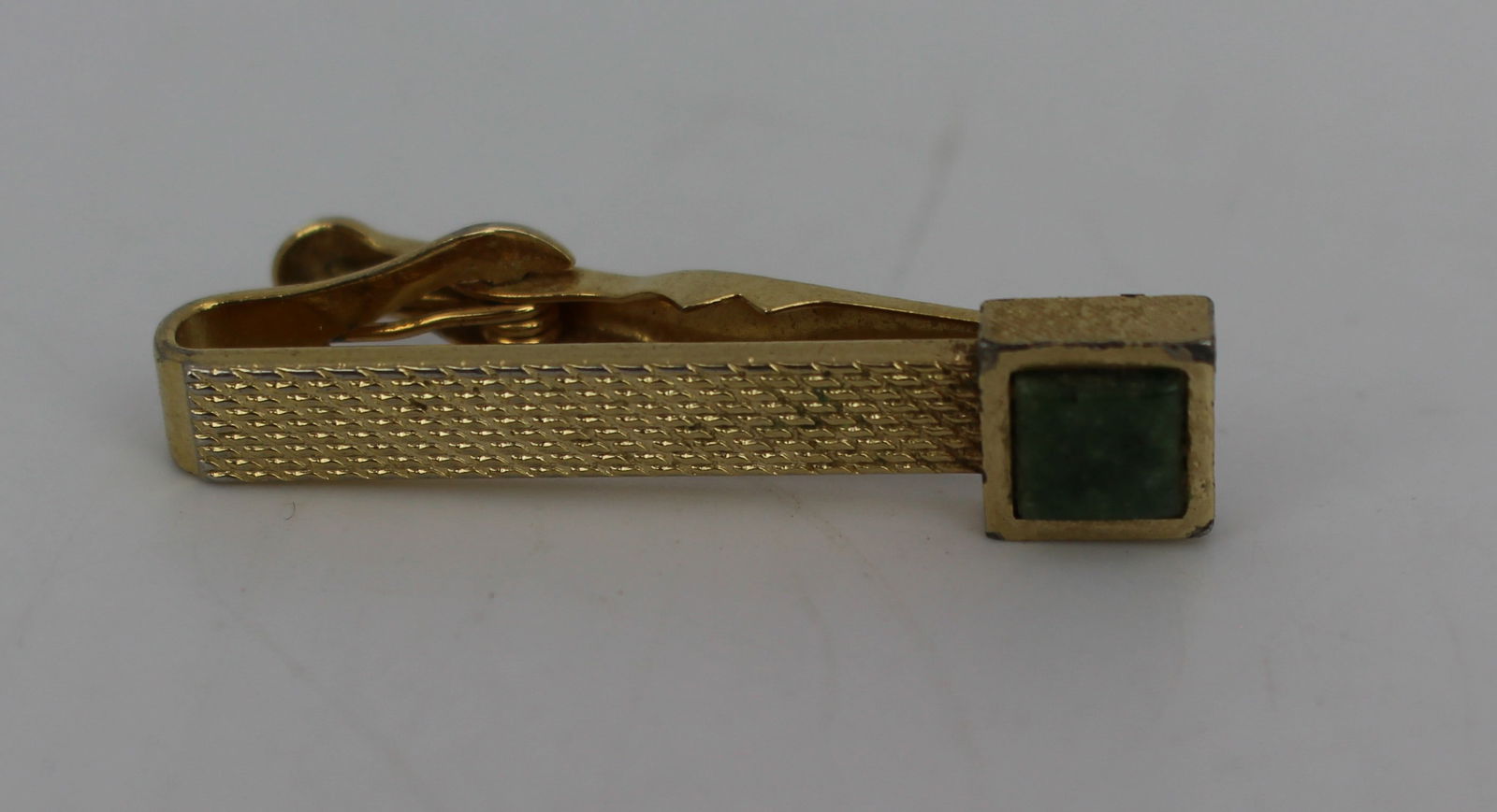 Vintage Gold Plated Jade Tie Clip: Title: Vintage Gold Plated Jade Tie Clip Description: Vintage Metal Tie Clip with Green Stone Material: Gold-tone metal Stone: Green stone, possibly jade or agate Design: Textured bar with