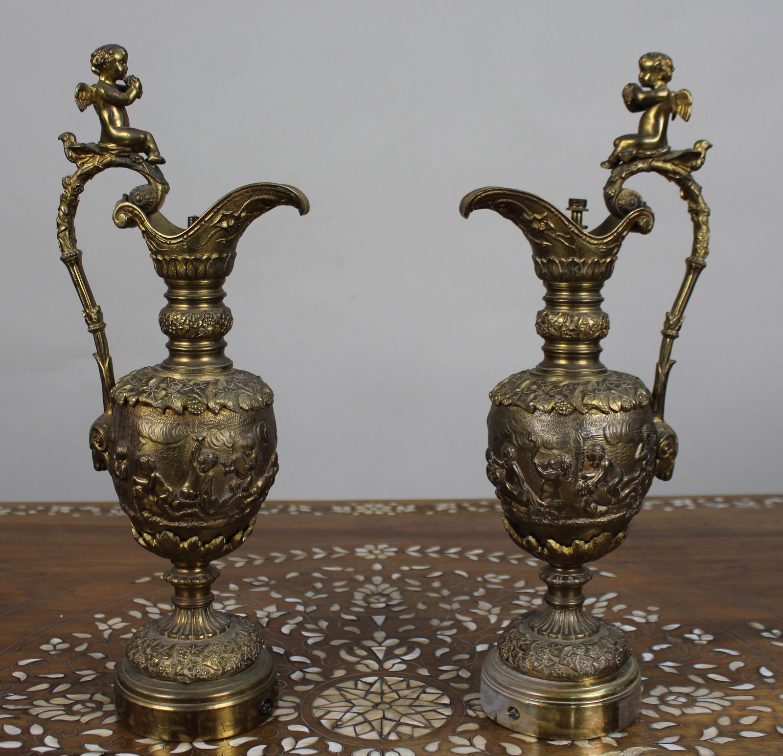Pair of 19th Century French Gilt Bronze Bacchanalian Ewers with Cherubs: Title: Pair of 19th Century French Gilt Bronze Bacchanalian Ewers with Cherubs Description: Pair of 19th Century French Gilt Bronze Bacchanalian Ewers with Cherubs A fine and decorative pair of