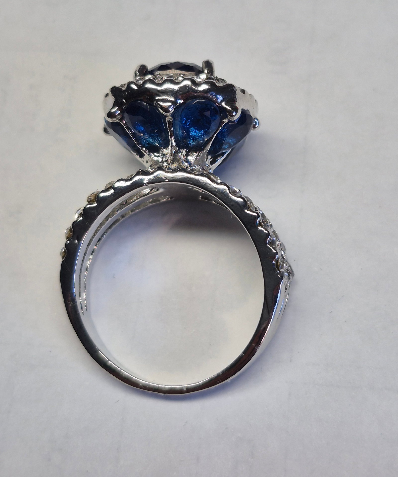 Silver-Plated Ring With Deep Blue Cushion-Cut Stone & Halo Accent Design: Title: Silver-Plated Ring With Deep Blue Cushion-Cut Stone & Halo Accent Design Description: Beautiful silver-plated ring featuring a striking deep-blue cushion-cut gemstone surrounded by a