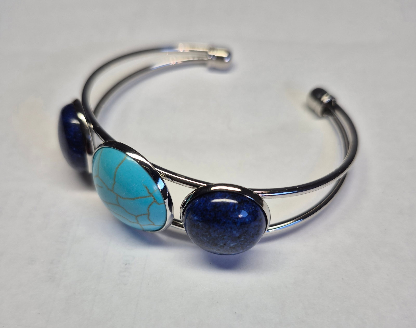 Stainless Steel Open Cuff Bracelet With Turquoise & Blue Stone Cabochons: Title: Stainless Steel Open Cuff Bracelet With Turquoise & Blue Stone Cabochons Description: Elegant open cuff bracelet crafted from polished stainless steel, featuring a vibrant turquoise centre