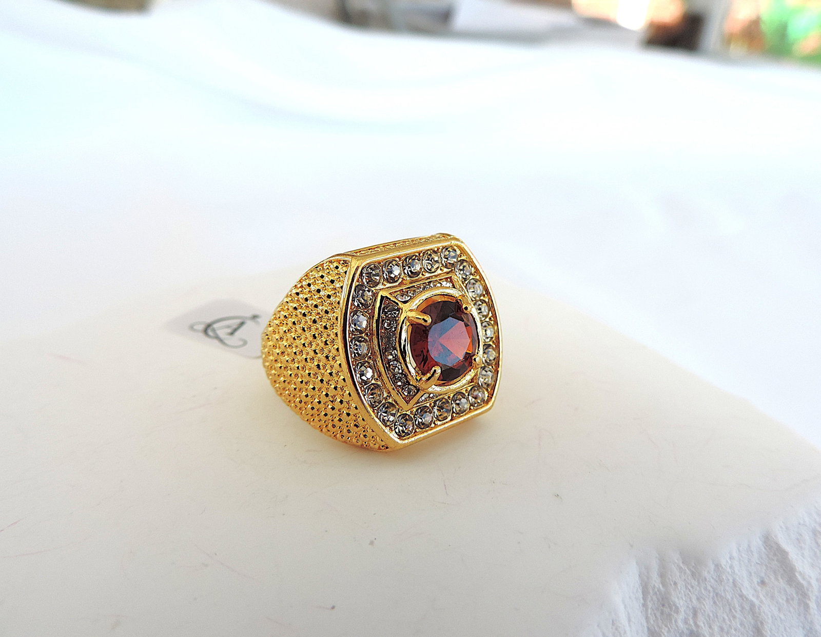 Aethon Men's 18k Gold Plated Zircon Ring: Title: Aethon Men's 18k Gold Plated Zircon Ring Description: Men's 18k gold plated ring set with a central red zircon and surrounded with white zircons. Ring size U1/2. (Part of