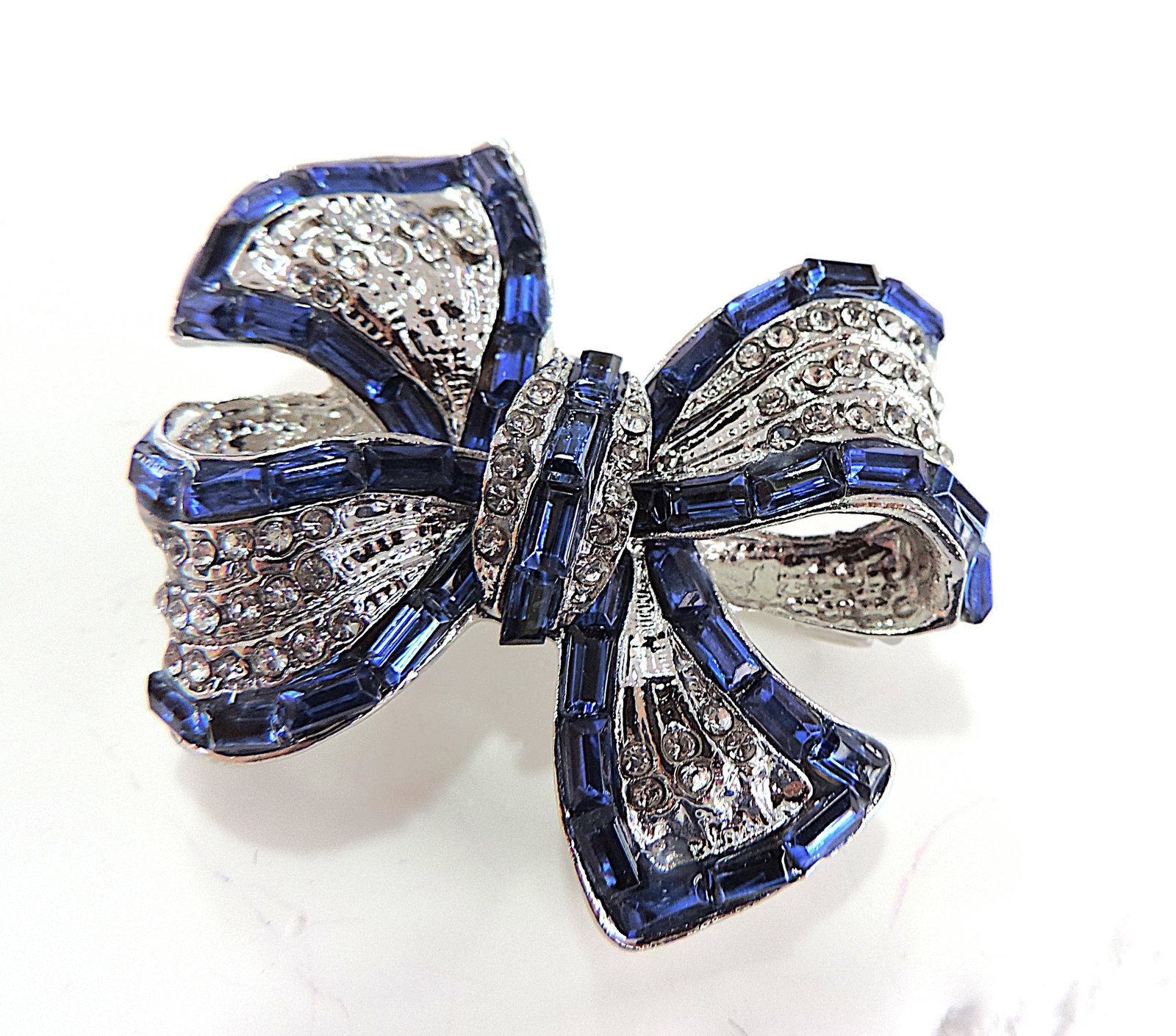 Blue & White Crystal Bow Brooch: Title: Blue & White Crystal Bow Brooch Description: A pretty bow shaped brooch in white tone metal set with blue & white crystals. Brooch measures 4x4cm and is in excellent condition.