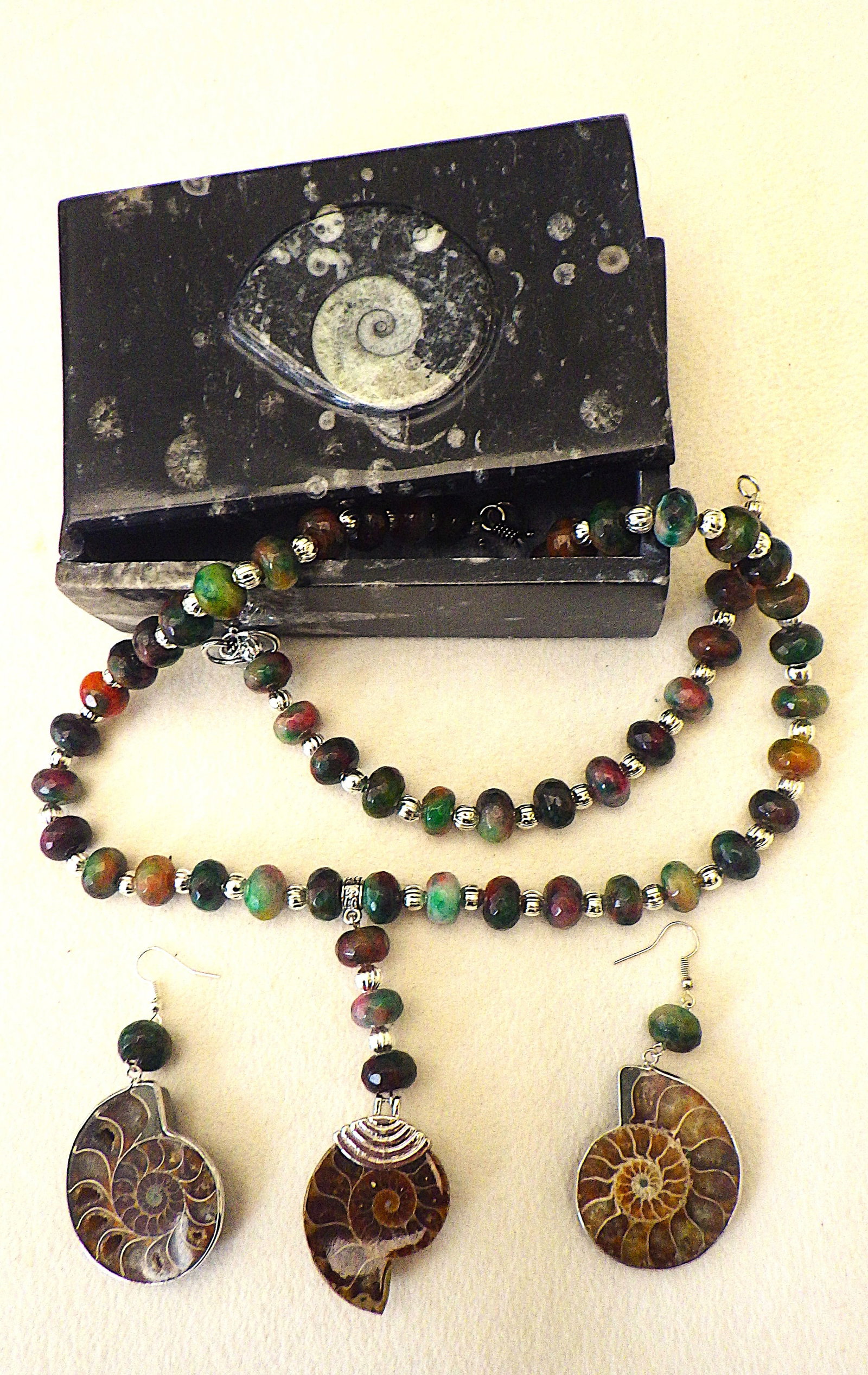 Necklace, bracelet & earrings with jade and Ammonites in Ammonite box: Title: Necklace, bracelet & earrings with jade and Ammonites in Ammonite box Description: A majestic multi coloured, faceted, Malaysian jade necklace, bracelet and earrings set with Triassic