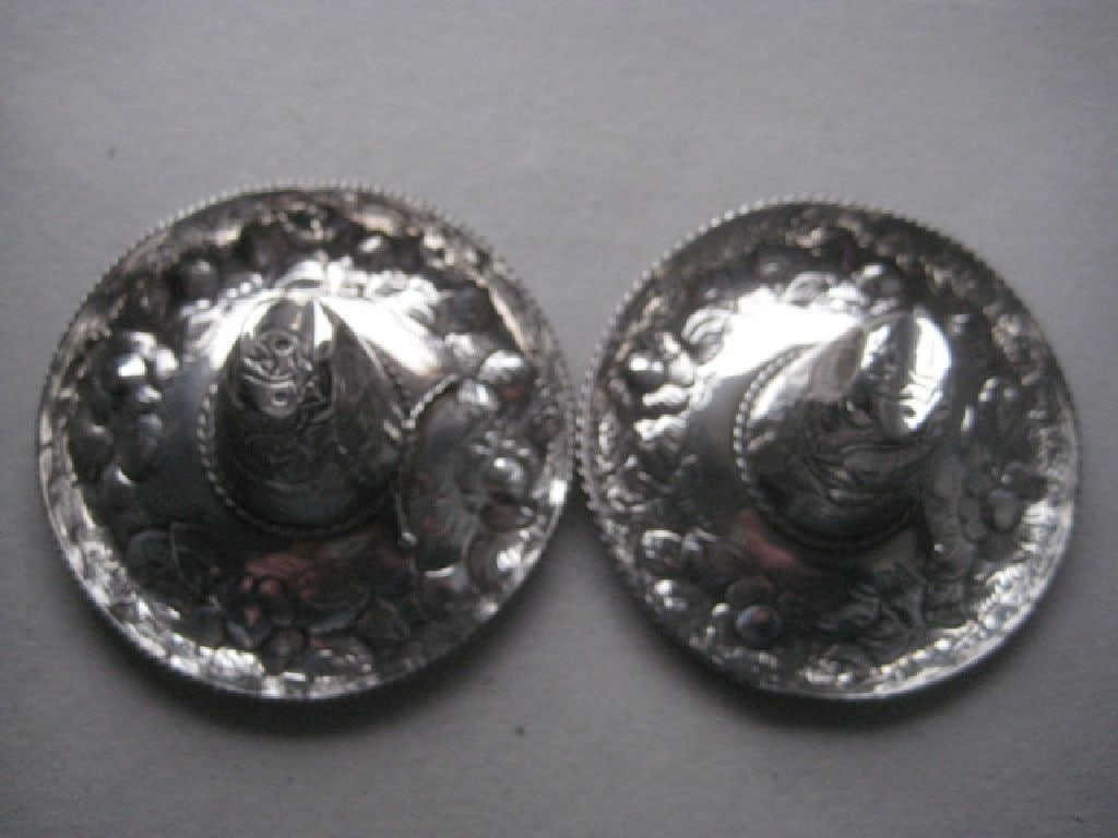 A Pair of Sterling Silver Mexican Sombrero Hats: Title: A Pair of Sterling Silver Mexican Sombrero Hats Description: They are both embossed with floral decoration. Stamped Sterling 925. Weight of them is 28.6 grams and 26.1 grams. Length is 3.5