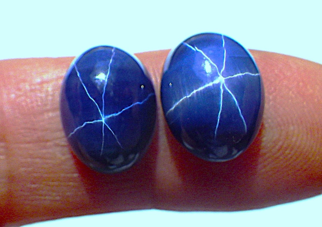Two blue star sapphire cabochons: Title: Two blue star sapphire cabochons Description: Two six ray Lindy star sapphire cabochons. Colour blue, with polished upper surface and unpolished backs. Total weight: 18.5 carats. Dimensions: