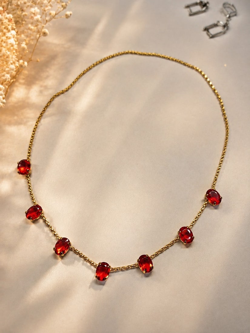 Gold-Tone Necklace with Synthetic Ruby Stones: Title: Gold-Tone Necklace with Synthetic Ruby Stones Description: Elegant gold-tone necklace set with seven faceted synthetic ruby stones in a classic oval shape. The vivid red stones are