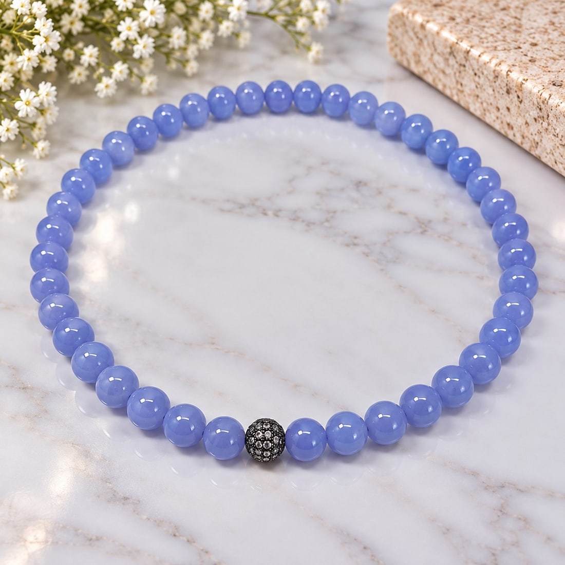 Blue Beaded Necklace with Crystal Accent: Title: Blue Beaded Necklace with Crystal Accent Description: Elegant necklace featuring polished blue round beads with a decorative crystal-set accent bead. A simple and attractive design with a be