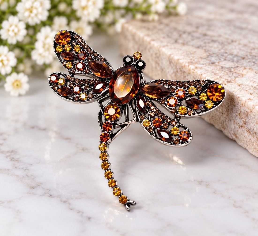 Amber Crystal Dragonfly Brooch: Title: Amber Crystal Dragonfly Brooch Description: An eye-catching dragonfly brooch in a silver-tone setting, decorated with sparkling amber, brown and golden-tone crystals. Features detailed