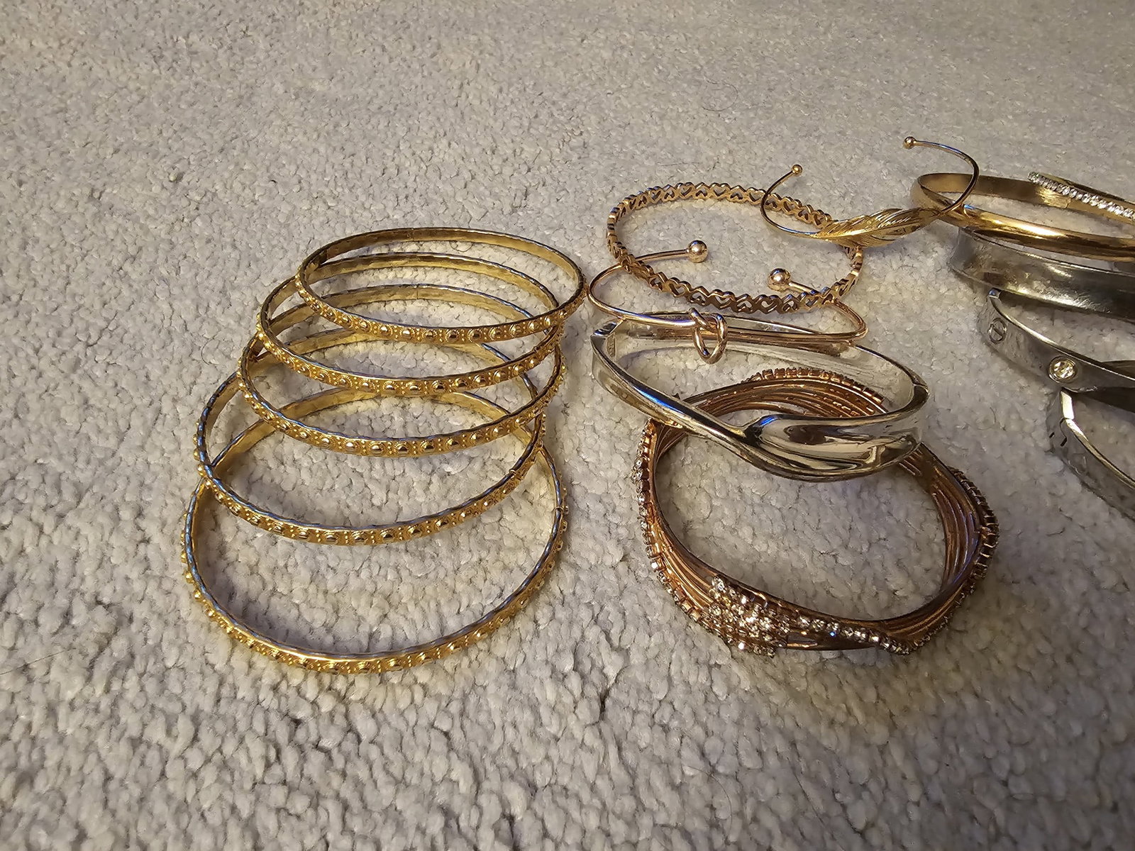 Lot of Gold Tone Bangles: Title: Lot of Gold Tone Bangles Description: A varied collection of decorative bangles and bracelets, comprising multiple examples of pierced, textured, twisted and polished design, predominantly in