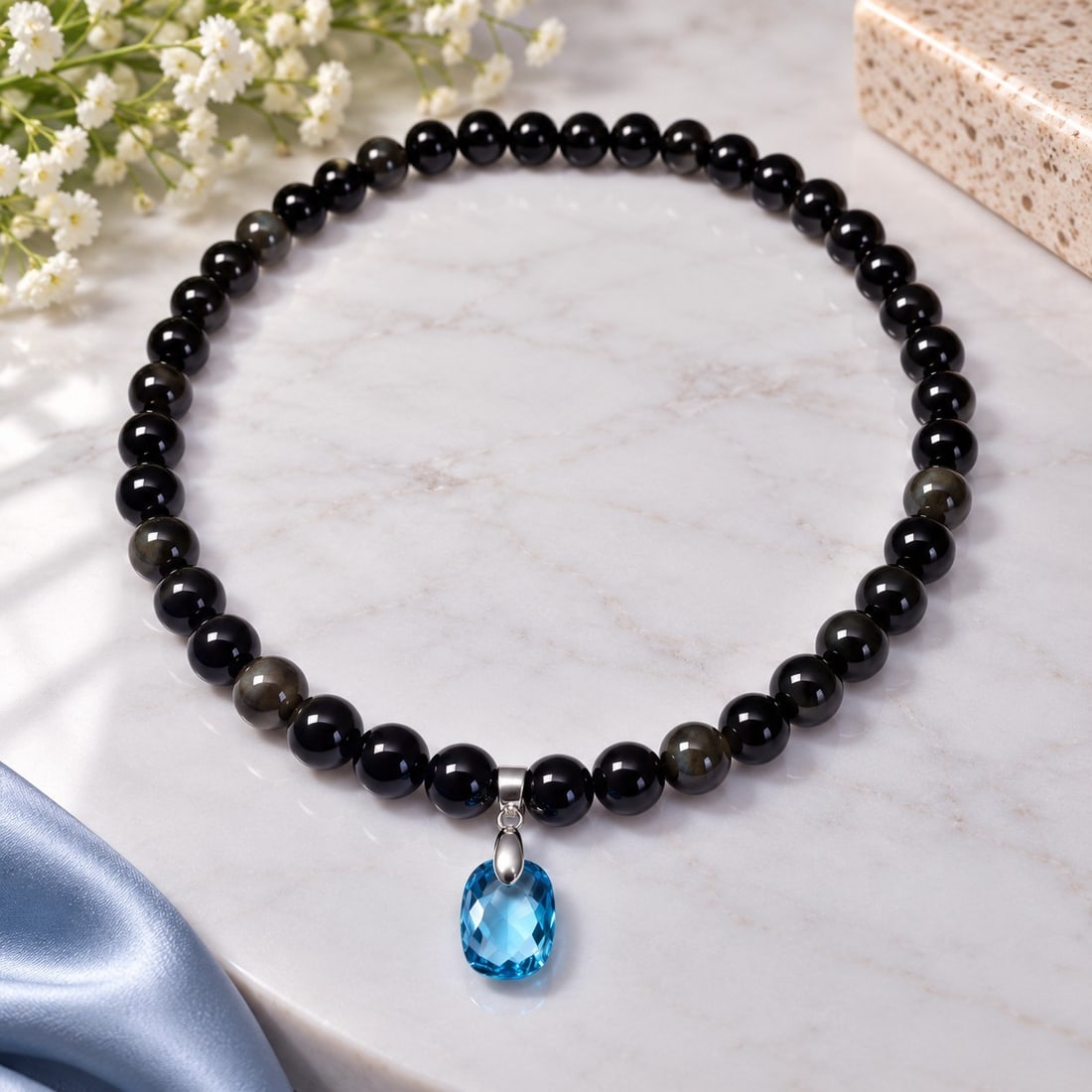 Black Bead Necklace with Natural Blue Topaz Pendant: Title: Black Bead Necklace with Natural Blue Topaz Pendant Description: Elegant necklace featuring polished black beads and a faceted natural blue topaz pendant. The vivid blue gemstone creates a