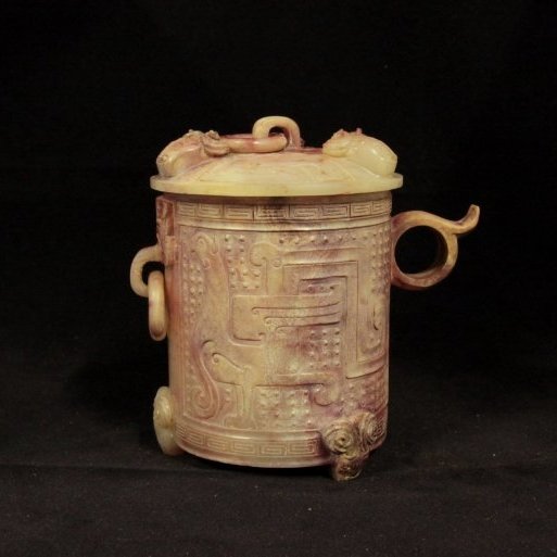 Western Han Dynasty Carved Jade Cup And Cover: Measurement: L 5.3 in., W 3.75 in., H 5.1 in. This was a finely carved cylindrical vessel raised on three animal mask feet, carved in relief around the sides with a confronting archaistic dragon and p