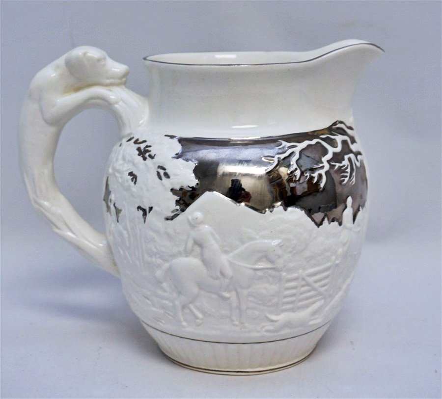 WEDGWOOD LUSTRE QUEENS WARE HUNT PITCHER: Wedgwood Queens Ware Pitcher, Cream and Silver Lustre, Hound Handle Hunt Scene. Circa 1940, excellent condition. Measures 8"x6"x7.25". Weight 1 pd 15 oz. PROVENANCE: A Charleston SC Private Estate.