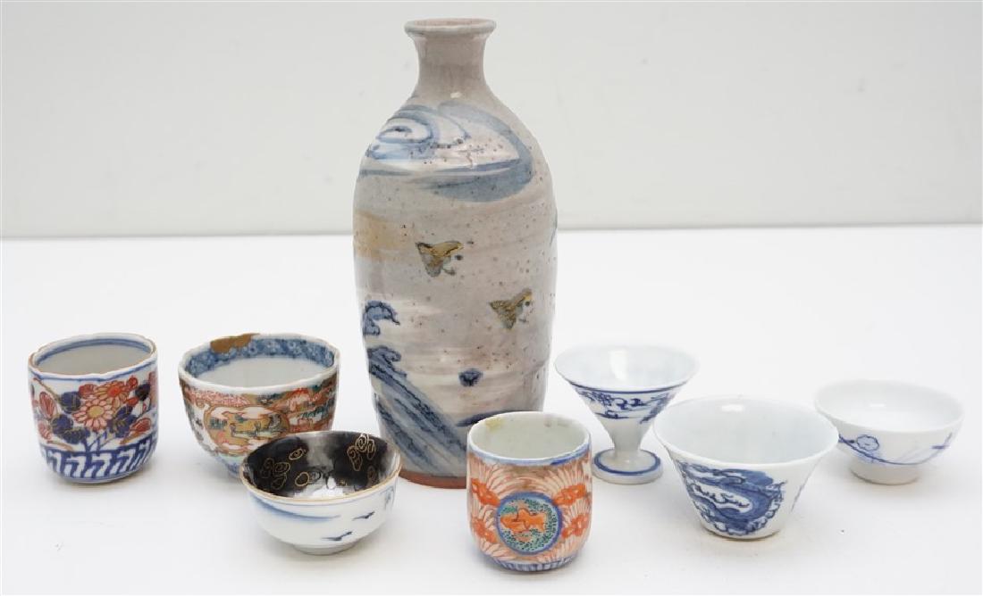 8 ANTIQUE KUTANI CEREMONIAL SAKE CUPS: Seven Antique Japanese Porcelain Ceremonial Sake Cups and one Vintage Sake Pottery Decanter. The decanter is signed and so are 3 of the 7 cups. Decanter in good condition. Cups are good, hairline to o
