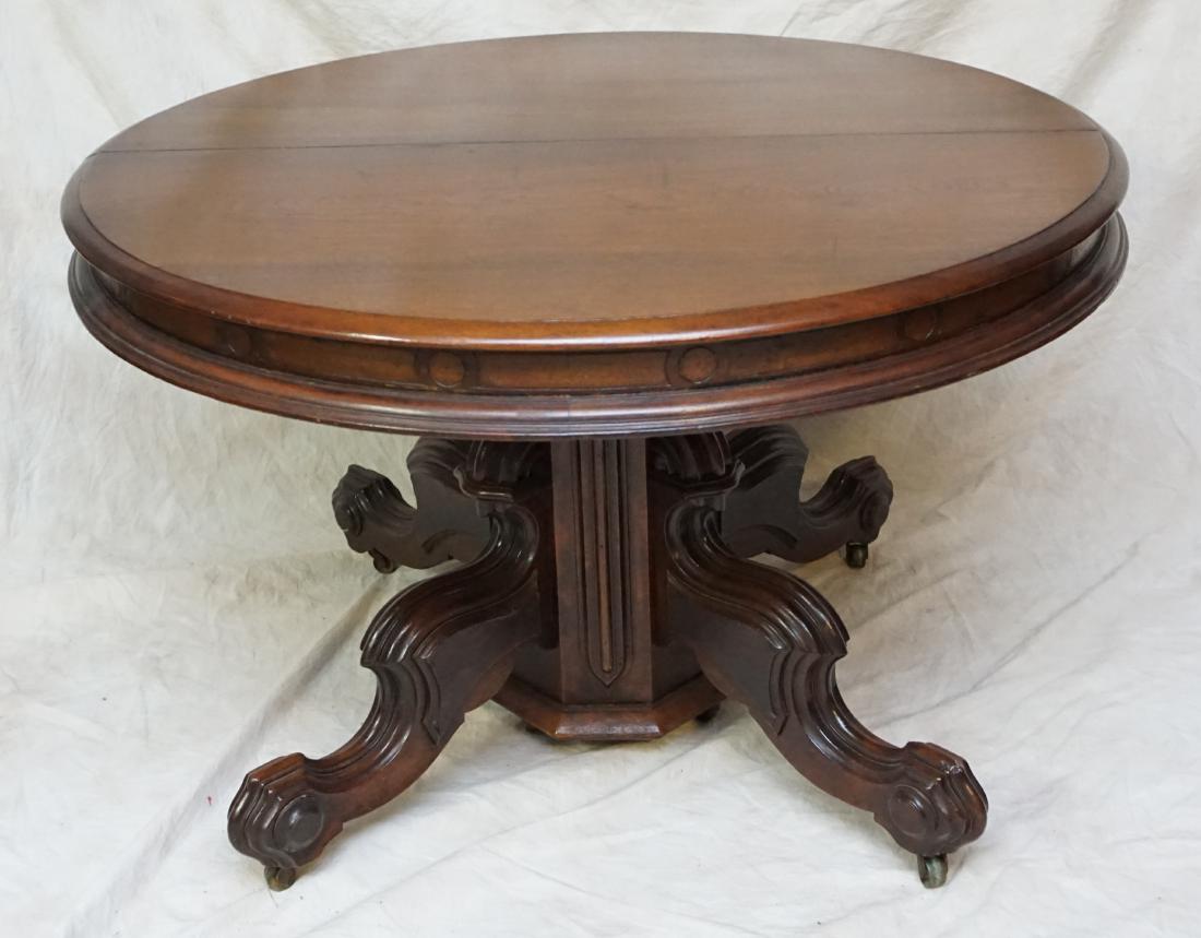 ANTIQUE WALNUT DINING TABLE: American walnut dining table having pedestal base with four carved legs ending in paw feet circa 1890. Table extends to 74.5" with the addition of two 12" leaves. 5"Measures 45" (closed) x 30 high; ea