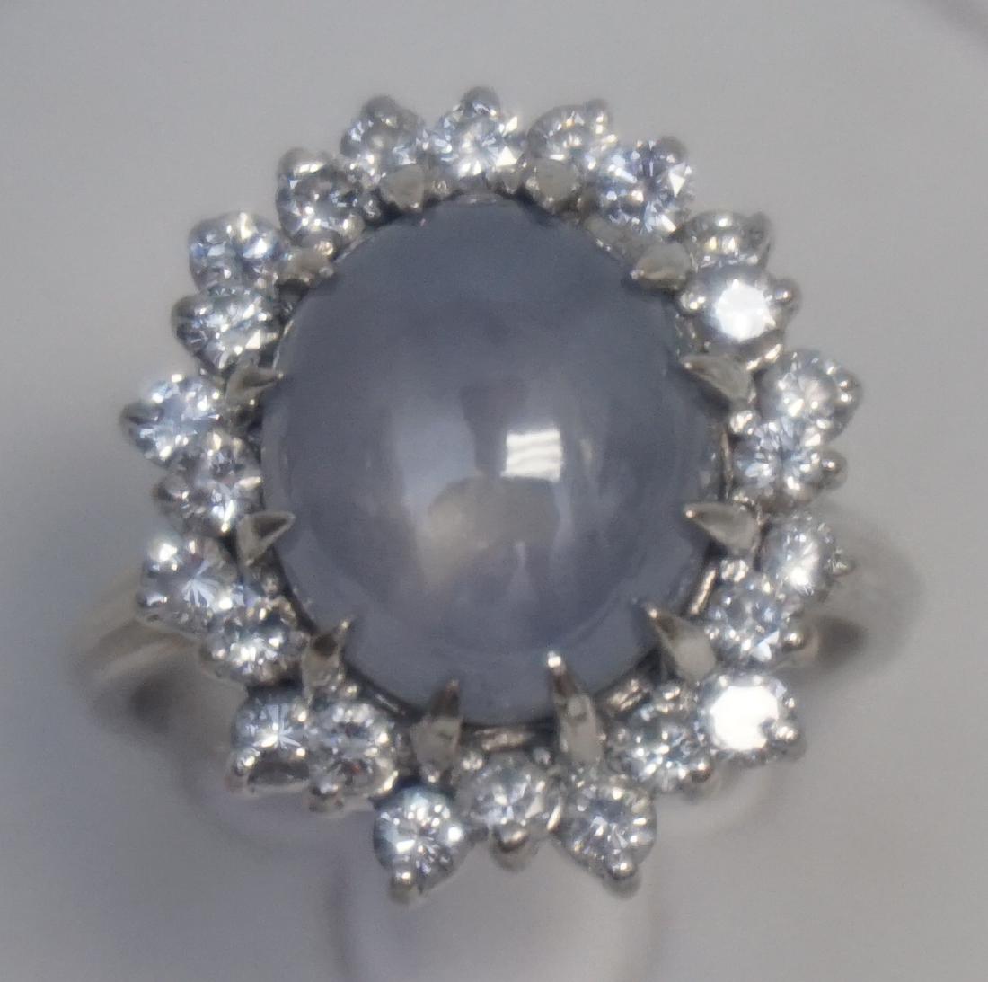 CATS EYE QUARTZ & DIAMOND RING- SIZE 5.75: One 14kt white gold cat’s eye quartz & diamond ring. The ring features one (1), prong set, oval cabochon cat’s eye quartz, with chatoyancy characteristics, in the center with a double halo of diam
