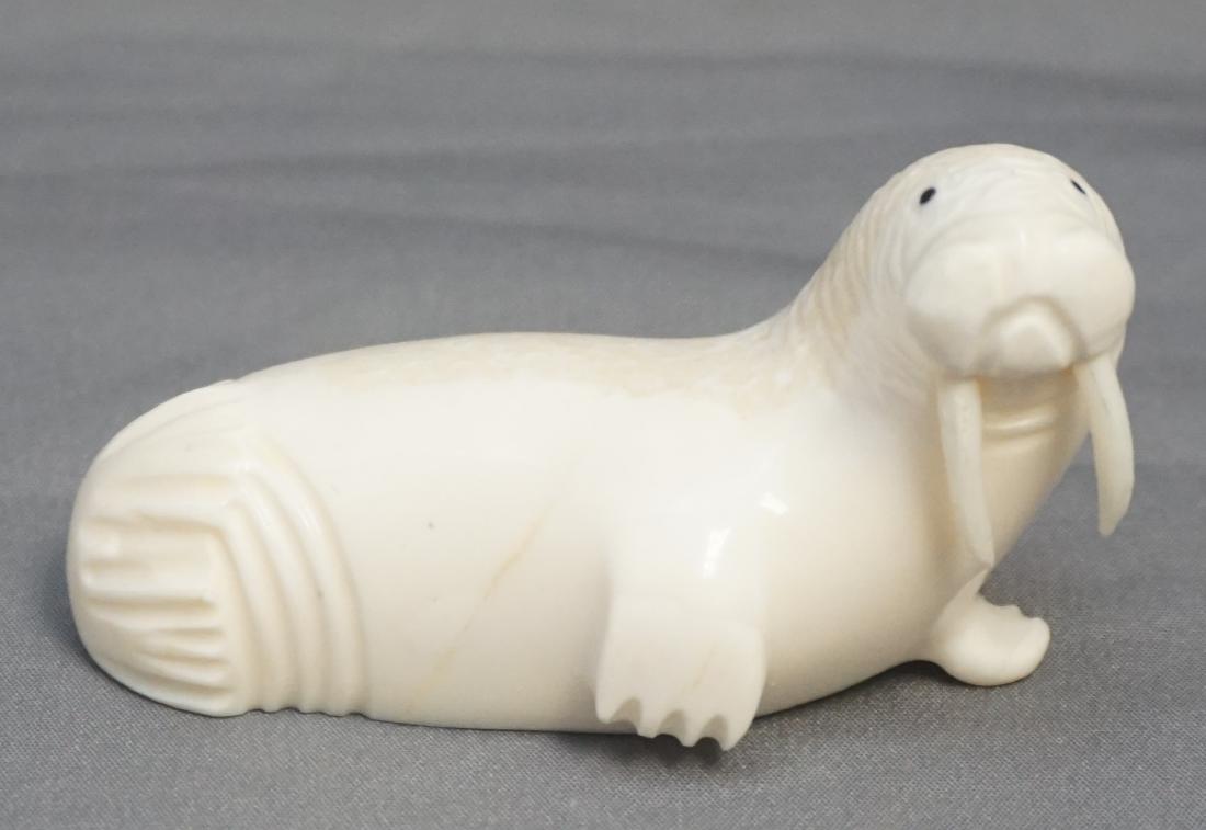 INUIT CARVED WALRUS SIGNED - WALRUS FOSSIL: Hand Carved Alaskan Walrus Fossil Walrus. Signed by the artist. Measures 2 1/2" long. Weight 2 oz. PROVENANCE: A Private Charleston SC Estate. Alaskan native collected and carved. It is a natural mate